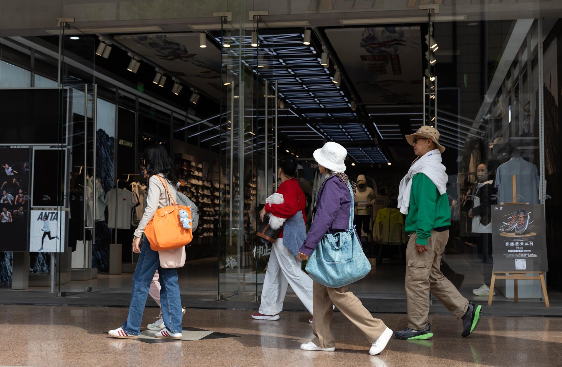 Peatones pasean frente a una tienda Anta en Pekín este jueves. Anta es una empresa china de ropa deportiva con sede en China que vende sus productos en Estados Unidos. EFE/EPA/JESSICA LEE