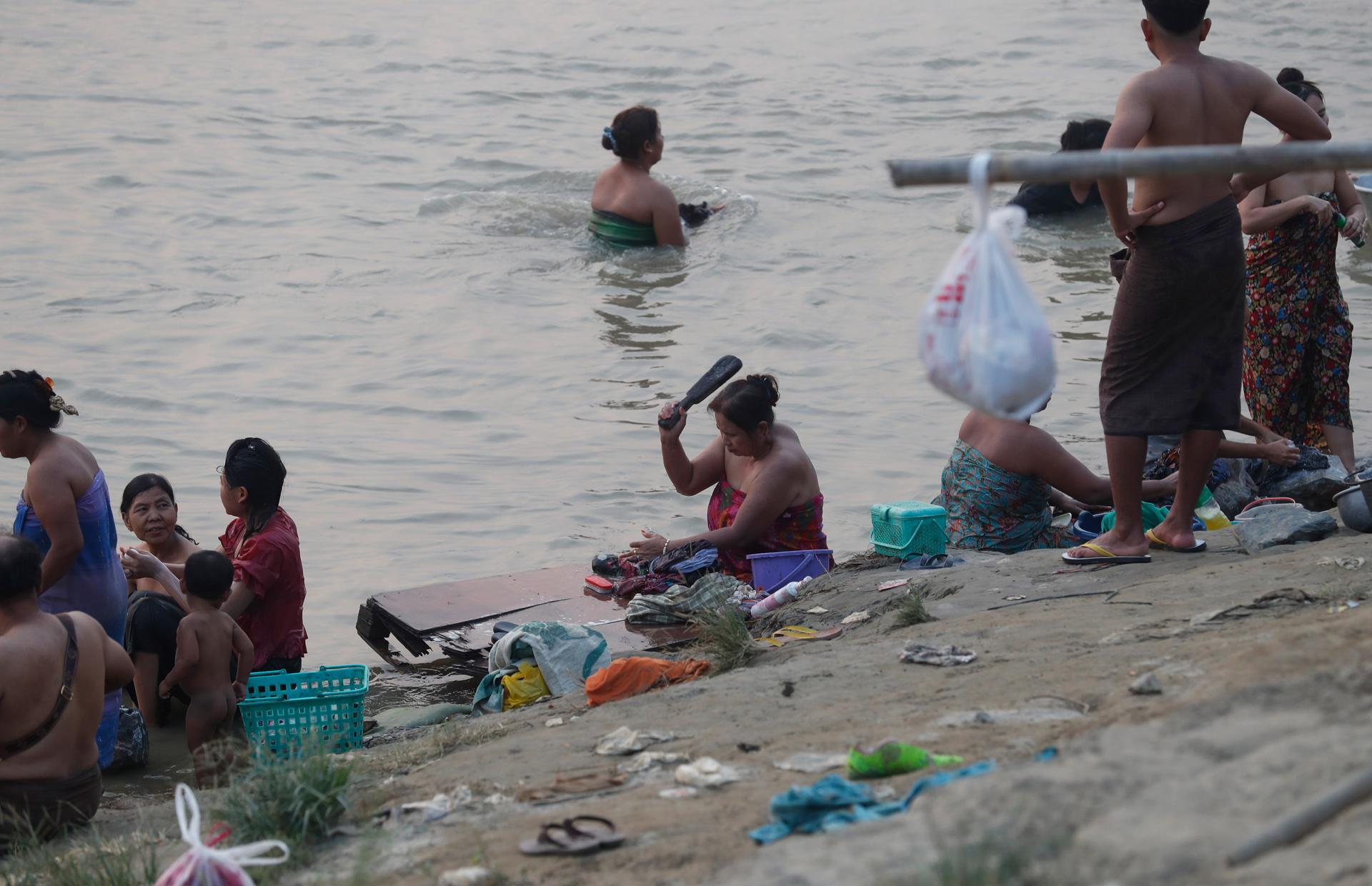 People wash clothes and take a bath in the river in Mandalay, Myanmar, 01 April 2025. ) EFE/EPA/NYEIN CHAN NAING