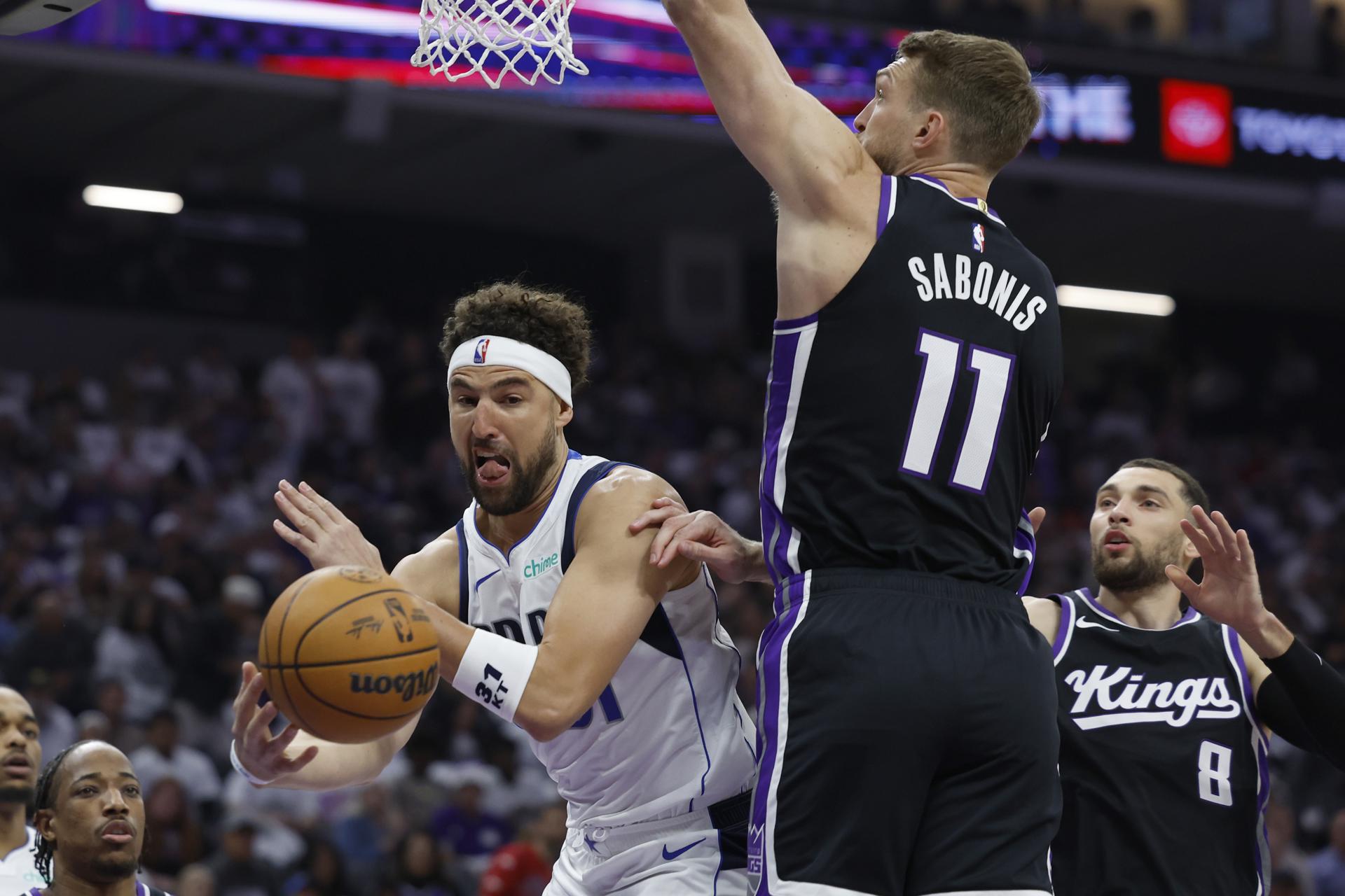 El escolta de los Dallas Mavericks Klay Thompson (I) pasa el balón ante la oposición del ala-pívot de los Sacramento Kings Domantas Sabonis (C). EFE/EPA/JOHN G. MABANGLO SHUTTERSTOCK FUERA