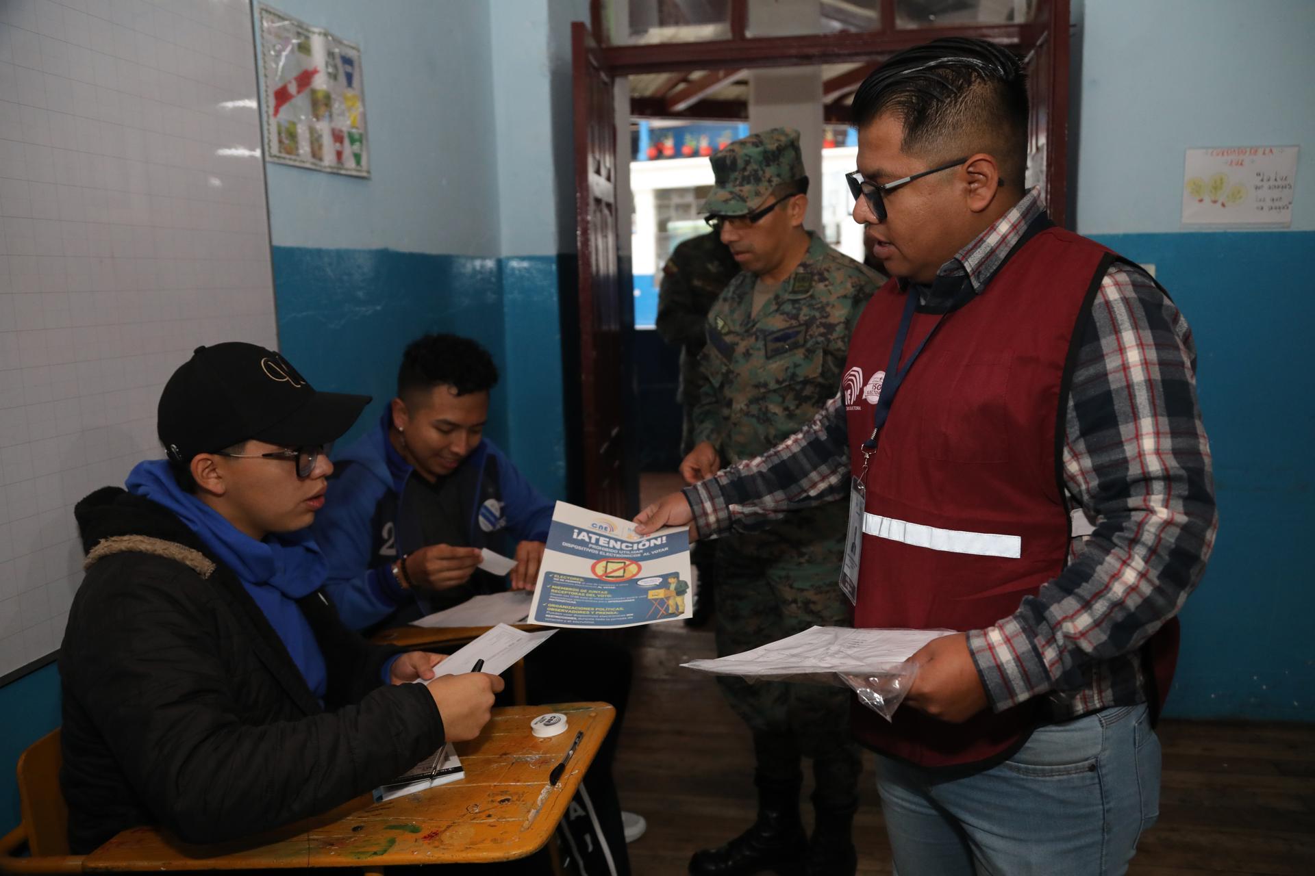 Un civil (d) y un militar (2d) antes de ejercer su derecho al voto, durante la segunda vuelta de los comicios presidenciales en Ecuador, este domingo, 13 de abril, en un colegio que ofició como centro de votación, en Quito. EFE/Gianna Benalcazar