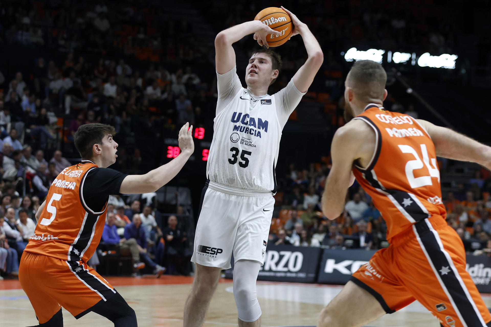 El jugador de UCAM Murcia, Simon Birgander (c), lanza ante los jugadores de Valencia Basket, Sergio de Larrea (i) y Matt Costello, durante el encuentro correspondiente a la fase regular de la Liga Endesa que disputan hoy sábado Valencia Basket y UCAM Murcia en el pabellón de la Fuente de San Luis de Valencia. EFE/Miguel Ángel Polo.