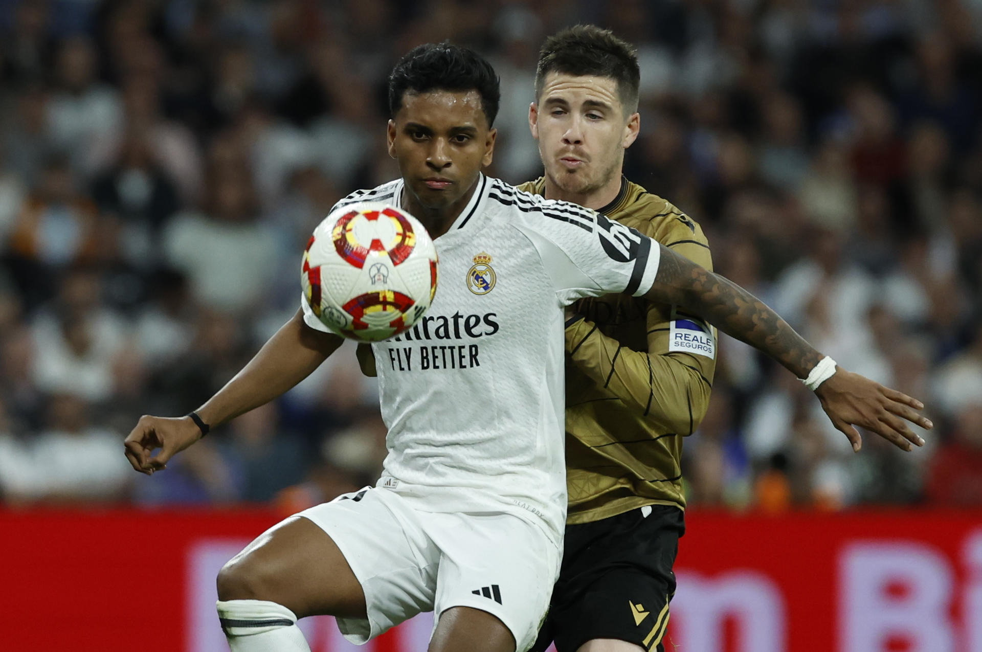 El delantero del Real Madrid Rodrygo Goes (i) juega un balón ante ante el defensa de la Real Sociedad Igor Zubeldia, durante el partido de vuelta de las semifinales de la Copa del Rey que Real Madrid y Real Sociedad disputan hoy martes en el estadio Santiago Bernabéu. EFE/Juanjo Martín