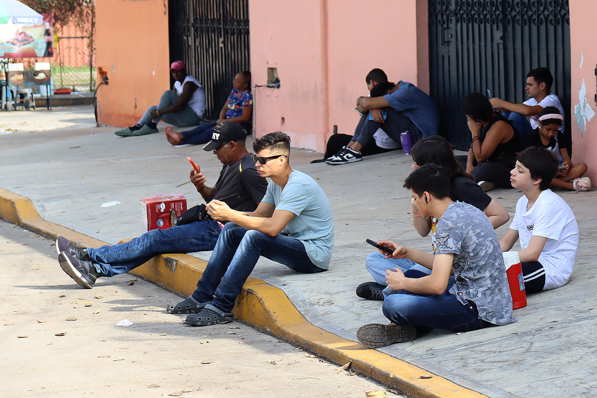 Migrantes observan sus teléfonos este viernes en el municipio de Tapachula, en el estado de Chiapas (México). EFE/ Juan Manuel Blanco