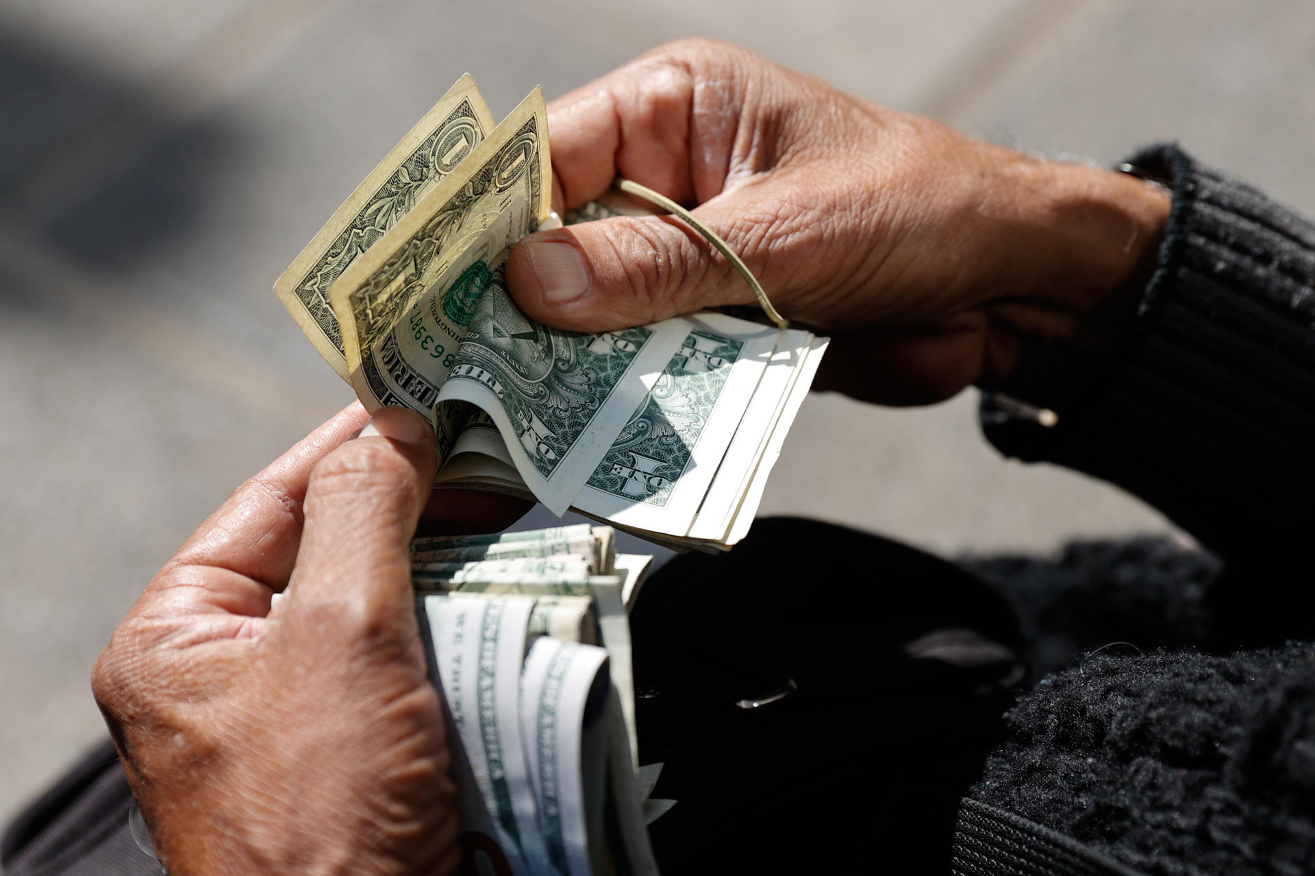 Fotografía de un cambista informal sosteniendo dolares. EFE/ Juan Pablo Pino
