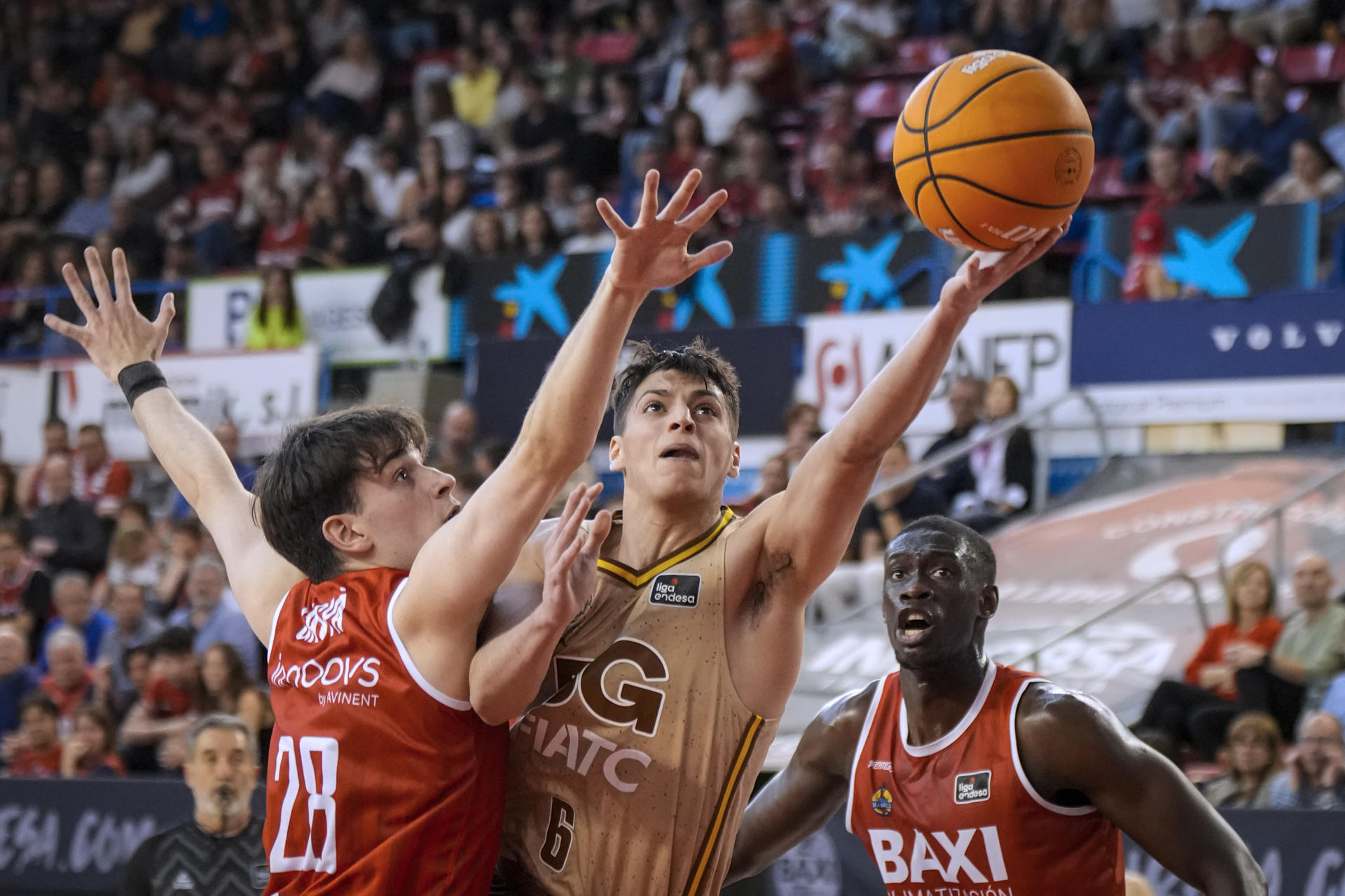 Juani Marcos (c), del Basquet Girona, entra a canasta defendido por Max Gaspá (i), del Baxi Manresa, durante el partido de la jornada 28 de la Liga Endesa que disputan Baxi Manresa y Basquet Girona este sábado en el pabellón Nou Congost de Manresa. EFE/ David Borrat