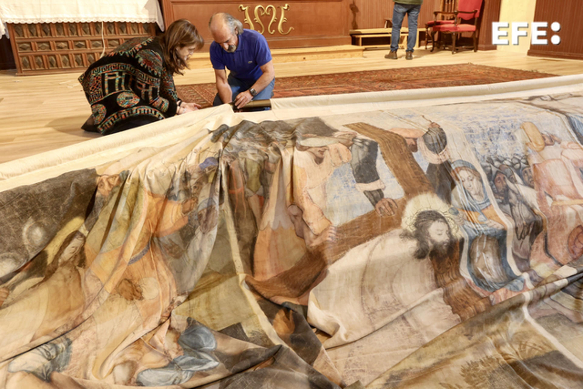 La asociación cultural 'La Colodra' ha colgado este sábado, la Sarga en la iglesia Nuestra Señora del Rosario. La sarga de Villoslada de Cameros, un gran lienzo policromado pintado en Amberes en el siglo XVI, cuelga durante toda la Semana Santa del retablo de su iglesia como escenografía de la representación teatral de 'La Pasión' y testimonio de la riqueza que disfrutó esta localidad riojana gracias a su actividad trashumante y el comercio de lana.-EFE/ Raquel Manzanares