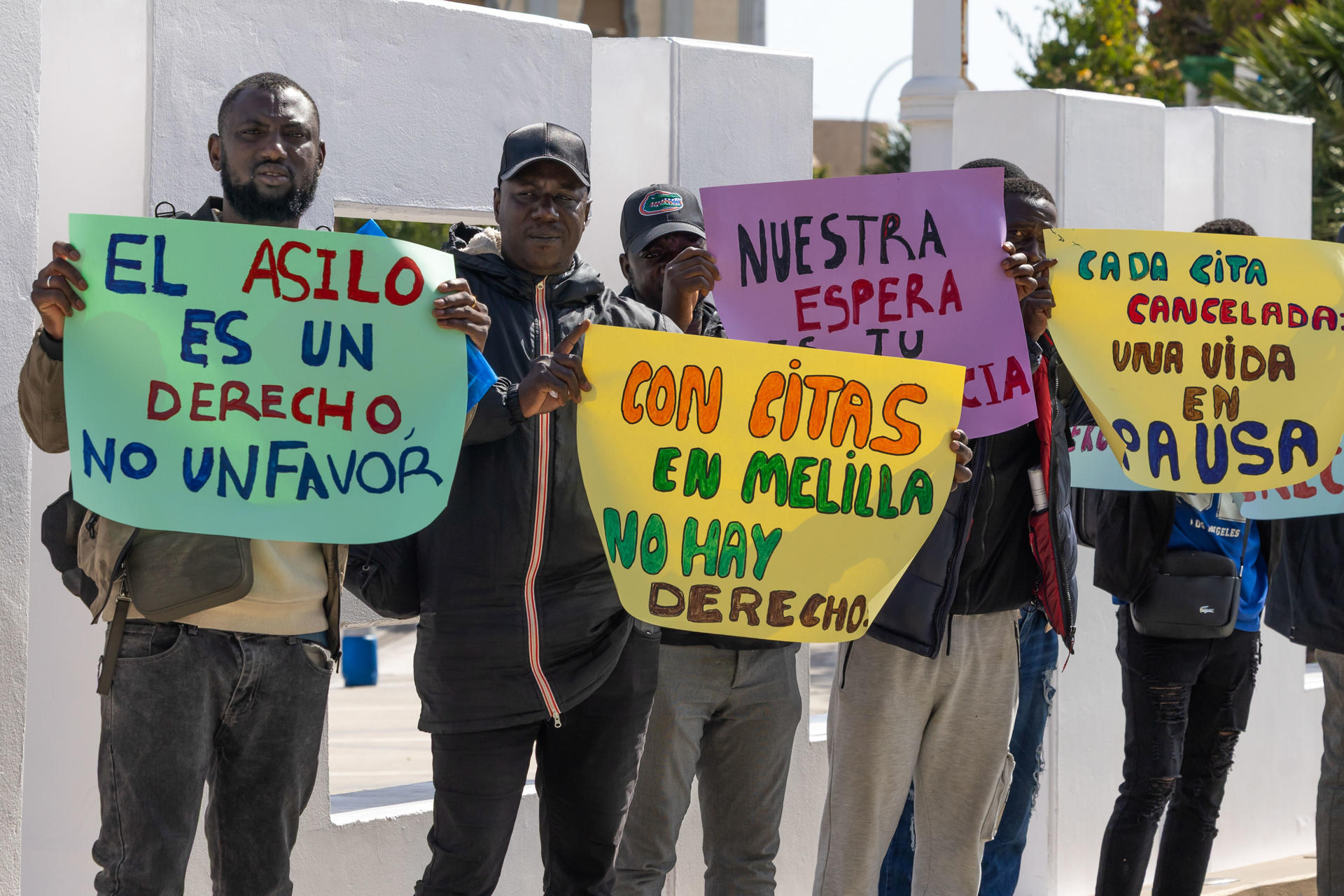 - Las asociaciones Geum Dodou y Mec de la Rue han denunciado este jueves, públicamente la situación de indefensión en la que se encuentran 10 solicitantes de asilo en Melilla que no han sido atendidos en la Oficina de Asilo pese a tener cita, lo que supone, a su juicio, una vulneración de un derecho fundamental. Siete de los migrantes afectados por esta situación, procedentes de Mali, se han concentrado frente a la Delegación del Gobierno en Melilla con pancartas en las que se podía leer El asilo es un derecho, no un favor; Cada cita cancelada es una vida en pausa; El derecho al asilo no se suspende o Asilo en Melilla: ni citas ni derechos. EFE/ José Manuel Giner