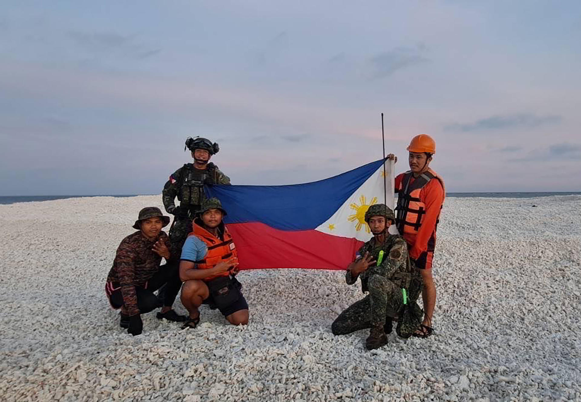 AME3180. CAYO SANDY (-), 28/04/2025.- Fotografía compartida por el portavoz de los guardacostas filipinos Jay Tarriela, en la red social X que muestra personas sosteniendo una bandera de Filipinas en Cayo Sandy. La Guardia Costera de China declaró este domingo que seis ciudadanos filipinos "desembarcaron ilegalmente" en Cayo Sandy (conocido en China como Tiexian), una pequeña isla en el mar de China Meridional cuya soberanía se disputan China y Filipinas. EFE/Jay Tarriela en la red social X /SOLO USO EDITORIAL/NO VENTAS/SOLO DISPONIBLE PARA ILUSTRAR LA NOTICIA QUE ACOMPAÑA (CRÉDITO OBLIGATORIO)MÁXIMA CALIDAD DISPONIBLE