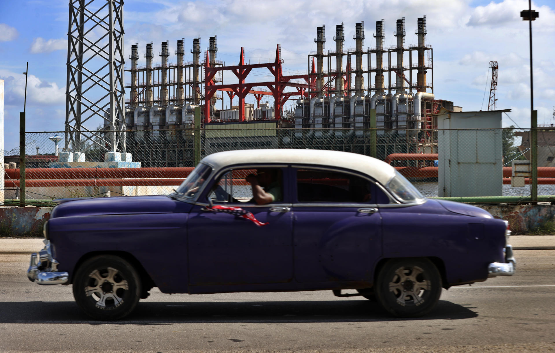 Un auto clásico pasa frente a una de las plantas de generación eléctrica en el puerto de La Habana (Cuba), en una fotografía de archivo. EFE/ Ernesto Mastrascusa