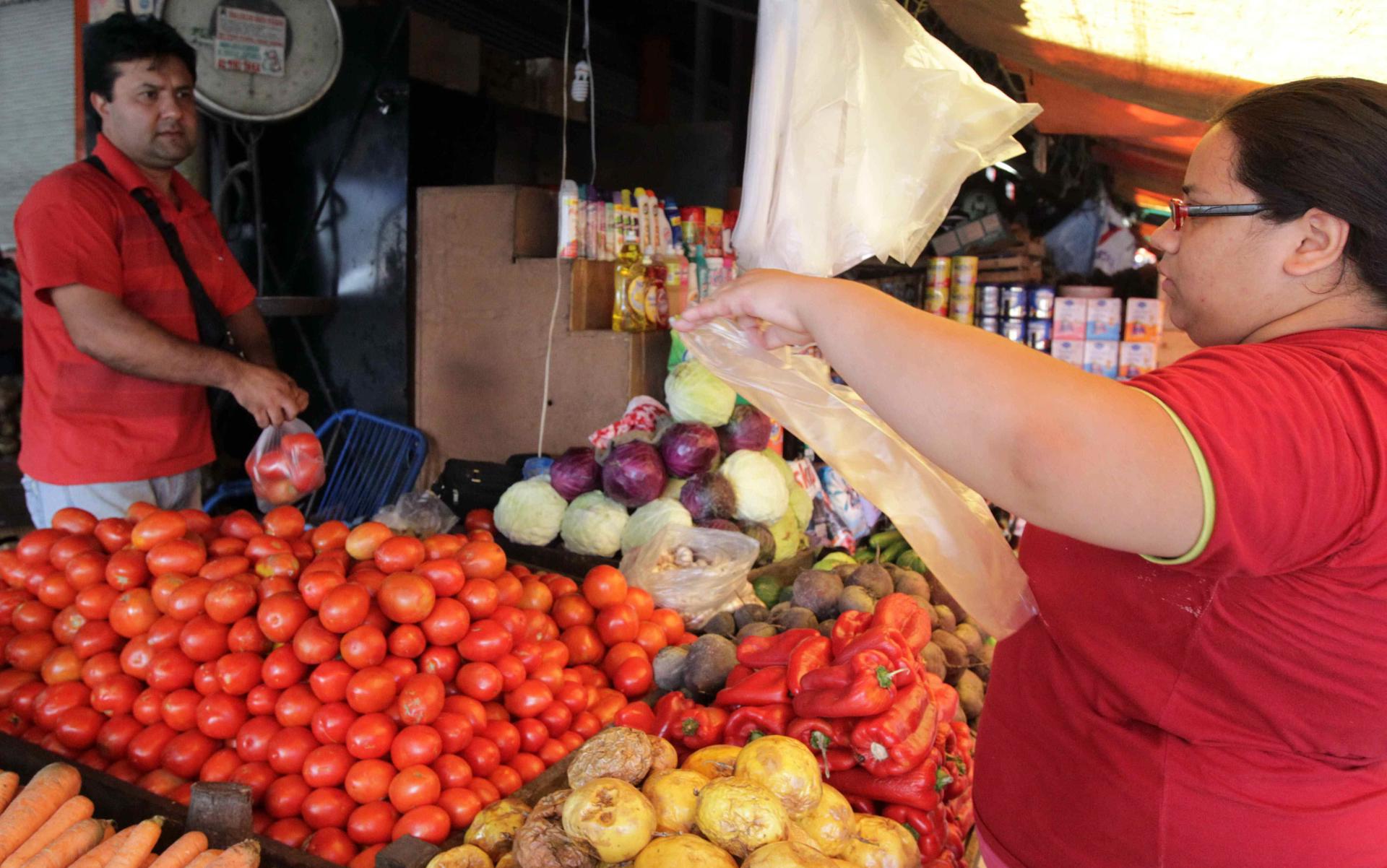 Fotografía de archivo que muestra a una mujer comprando alimentos en un mercado de Asunción (Paraguay). EFE/Andrés Cristaldo