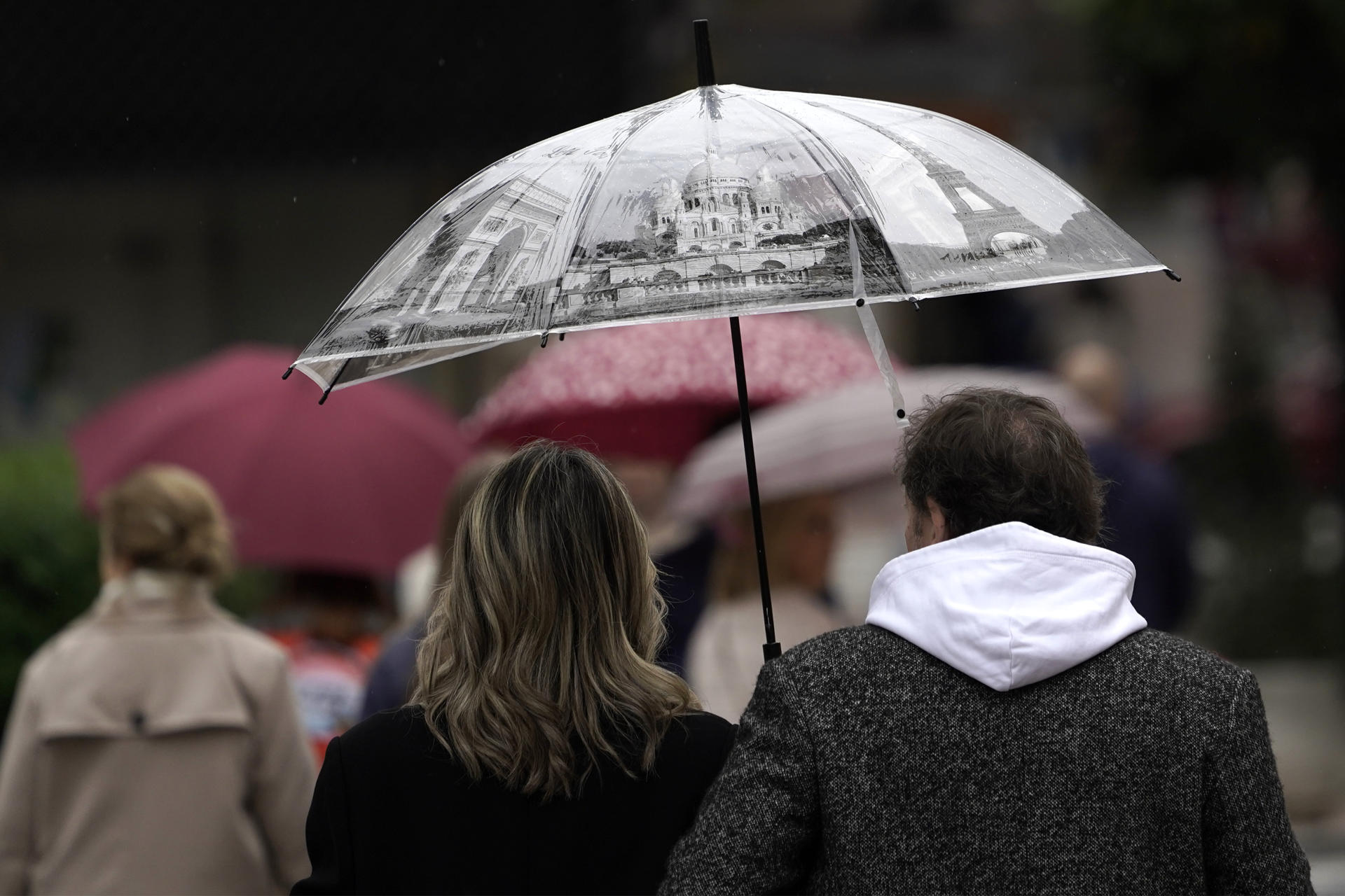 Viandantes con paraguas en las inmediaciones del hotel de la Reconquista este viernes. Una nueva borrasca se está acercando este viernes a la Península, entrando por Galicia, y dejará lluvia y nieve en zonas altas en el cuadrante noroeste peninsular. EFE/Paco Paredes