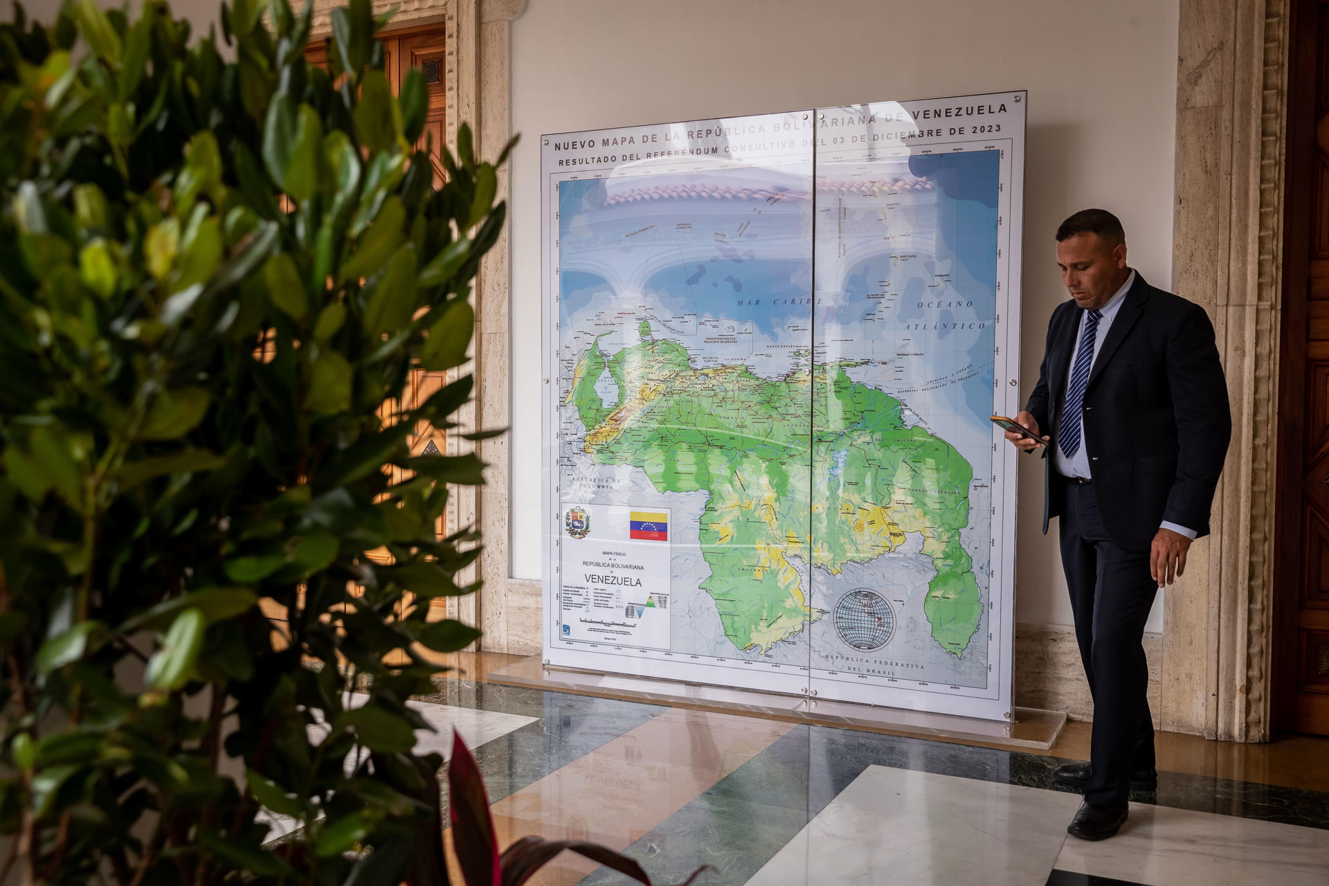 Fotografía de archivo en la que aparece un hombre junto a un mapa de Venezuela en el que ya está anexado el Esequibo, territorio de 160.000 kilómetros cuadrados que disputa con Guyana, en Caracas (Venezuela). EFE/Rayner Peña