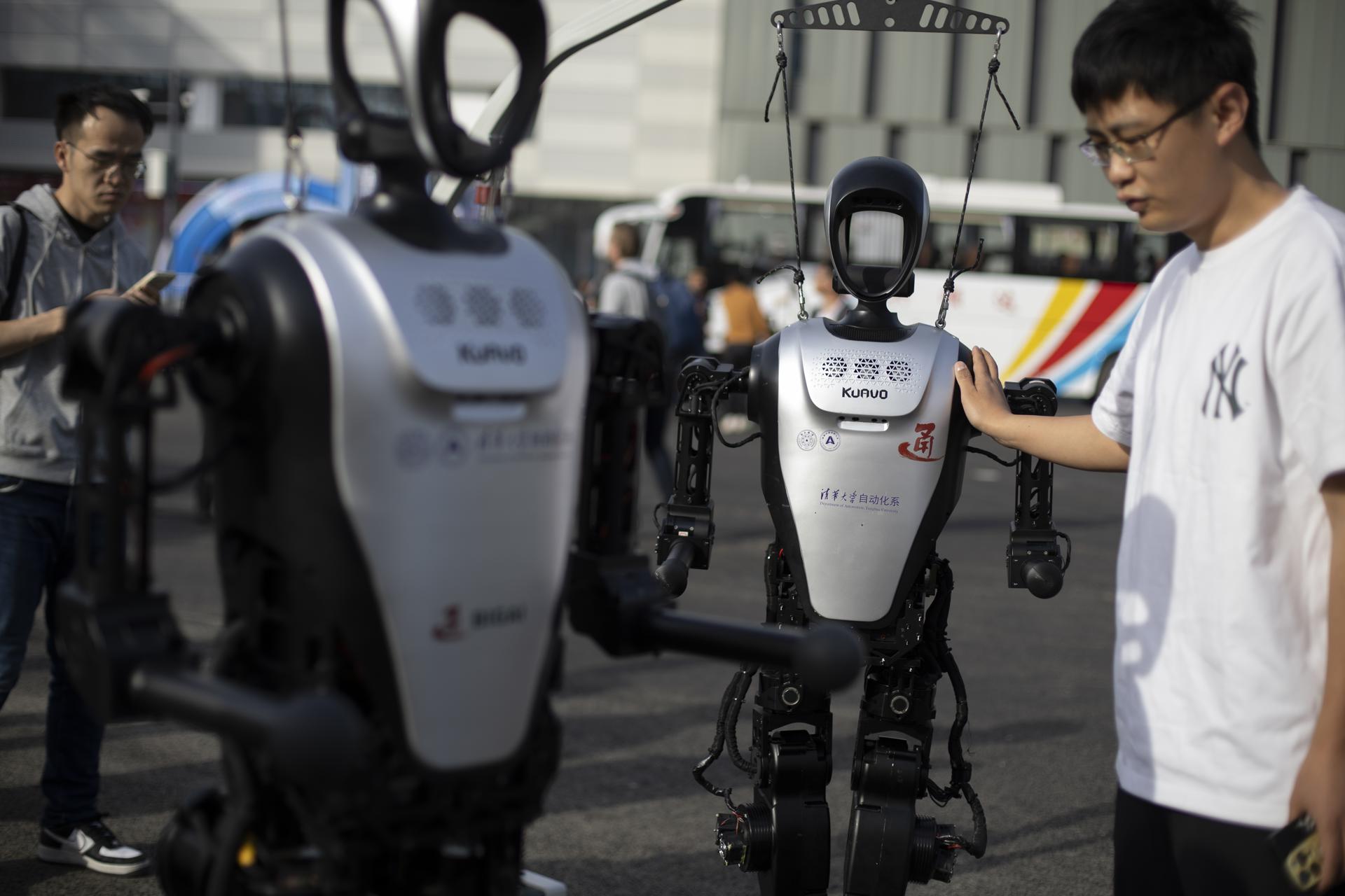 Un técnico observa un robot humanoide antes de una carrera entre humanos y robots en Pekín. EFE/EPA/ANDRÉS MARTÍNEZ CASARES