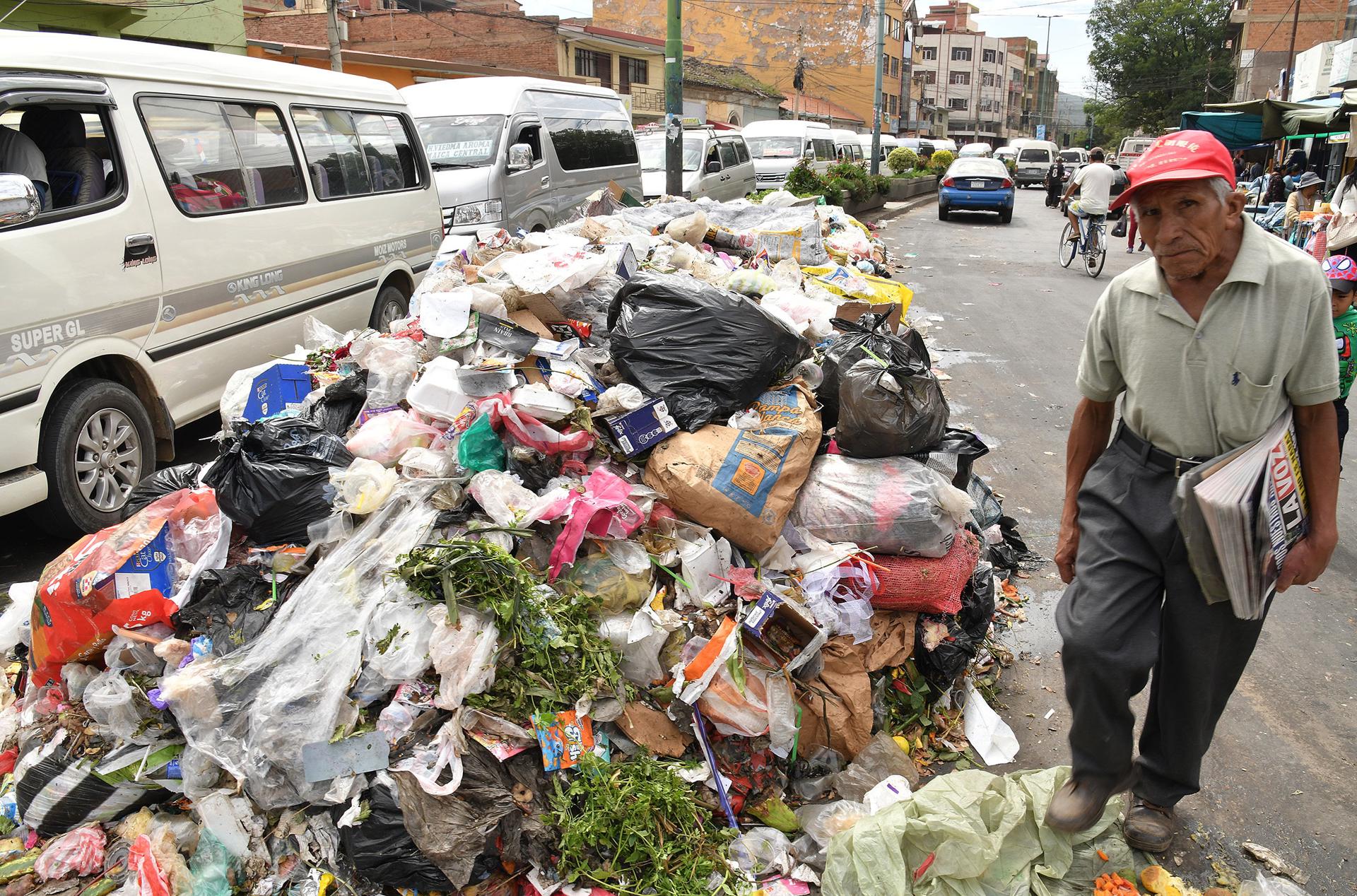 Un hombre pasa al lado de bolsas de basura este jueves, en Cochabamba (Bolivia). EFE/Jorge Ábrego