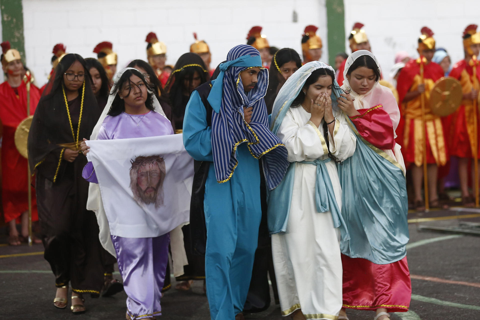 Un grupo de estudiantes de la escuela parroquial Domingo Savio personifican a un grupo de mujeres y discípulos de Jesucriusto, durante una recreación del Vía Crucis, en San Salvador (El Salvador). EFE/Rodrigo Sura