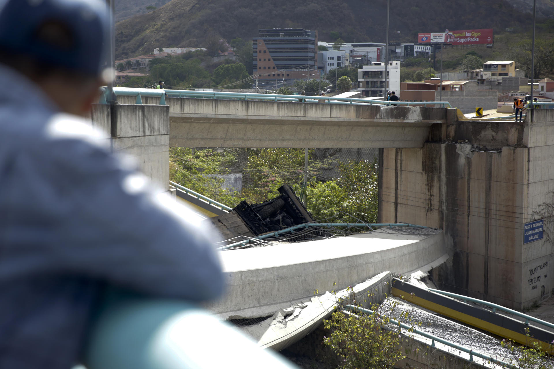 Una persona observa una máquina recicladora de asfalto tras el colapso de una parte de un puente aéreo este sábado, en de Tegucigalpa (Honduras). EFE/ Gustavo Amador