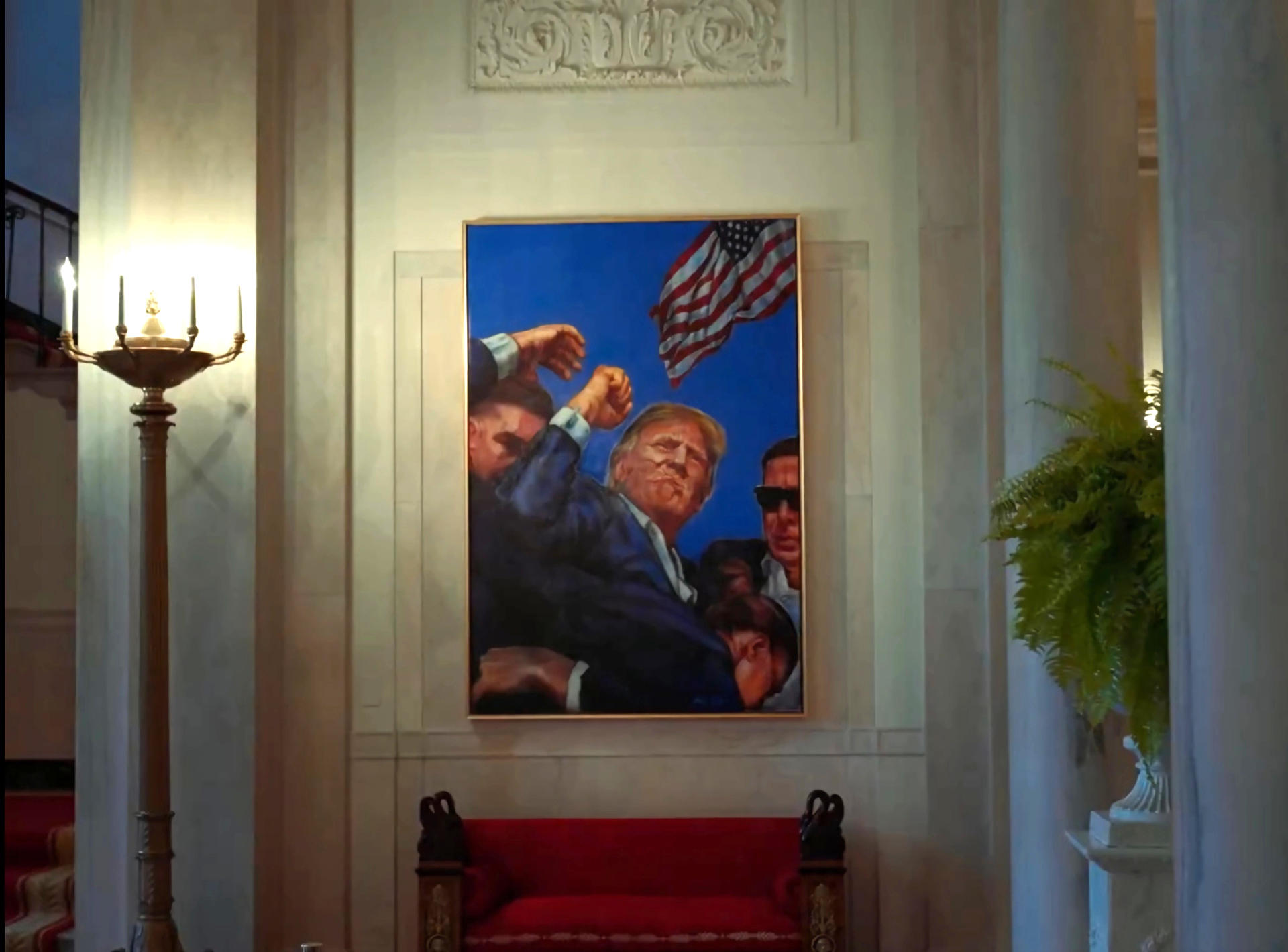 Captura de un video divulgado por la Casa Blanca en su cuenta oficial en la red social X de un cuadro en el que aparece Trump con el puño en alto y la cara ensangrentada, escoltado por agentes del Servicio Secreto y con una bandera estadounidense ondeando de fondo, colgado en La Casa Blanca en Washington. EFE/La Casa Blanca