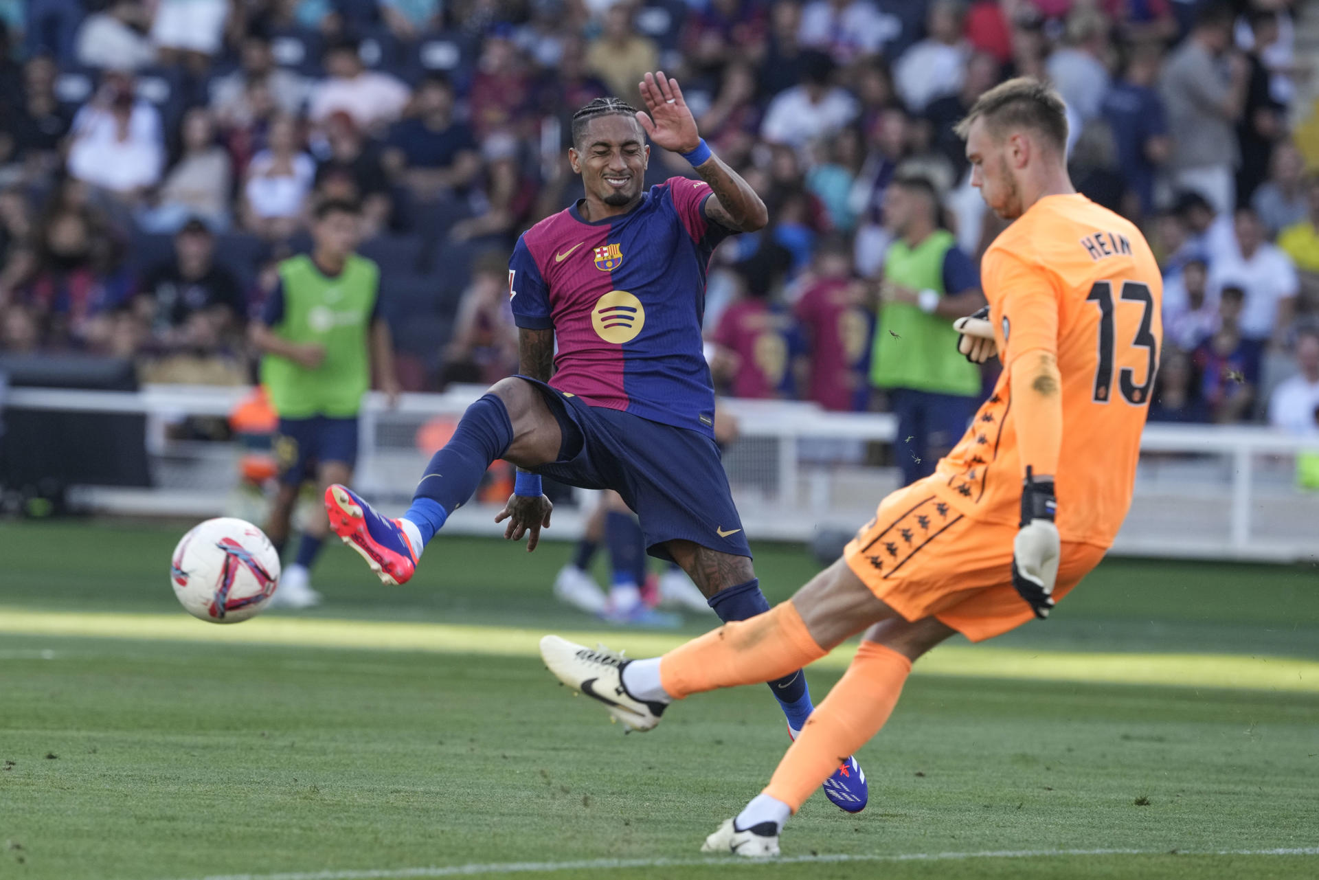 El delantero brasileño del Barcelona Raphinha (i) presiona al portero estonio del Valladolid Karl Hein durante el partido de LaLiga que disputaron ambos conjuntos el 31 de agosto en el estadio Olímpico Lluis Companys. EFE/ Alejandro Garcia