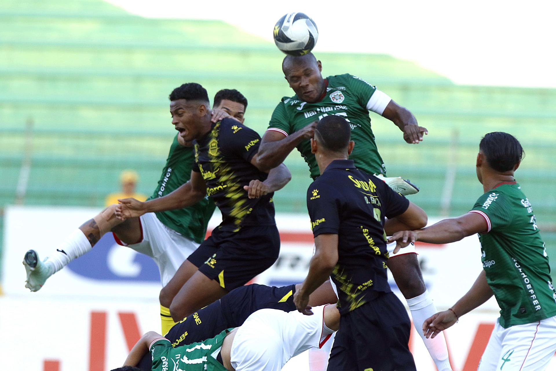 Juan Anangonó (c) de Marathón disputa el balón con Yeison Moreno (i) de Real España durante el clásico hondureño que su equipo ganó este domingo en el estadio Olímpico de San Pedro Sula. EFE/Jose Valle