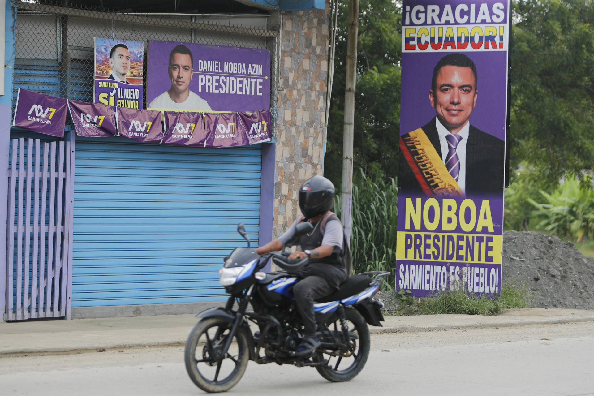 Un motociclista pasa frente a una imagen del presidente de Ecuador y candidato a la reelección, Daniel Noboa, este 12 de abril de 2025, en Olón (Ecuador).EFE/ Carlos Durán Araújo