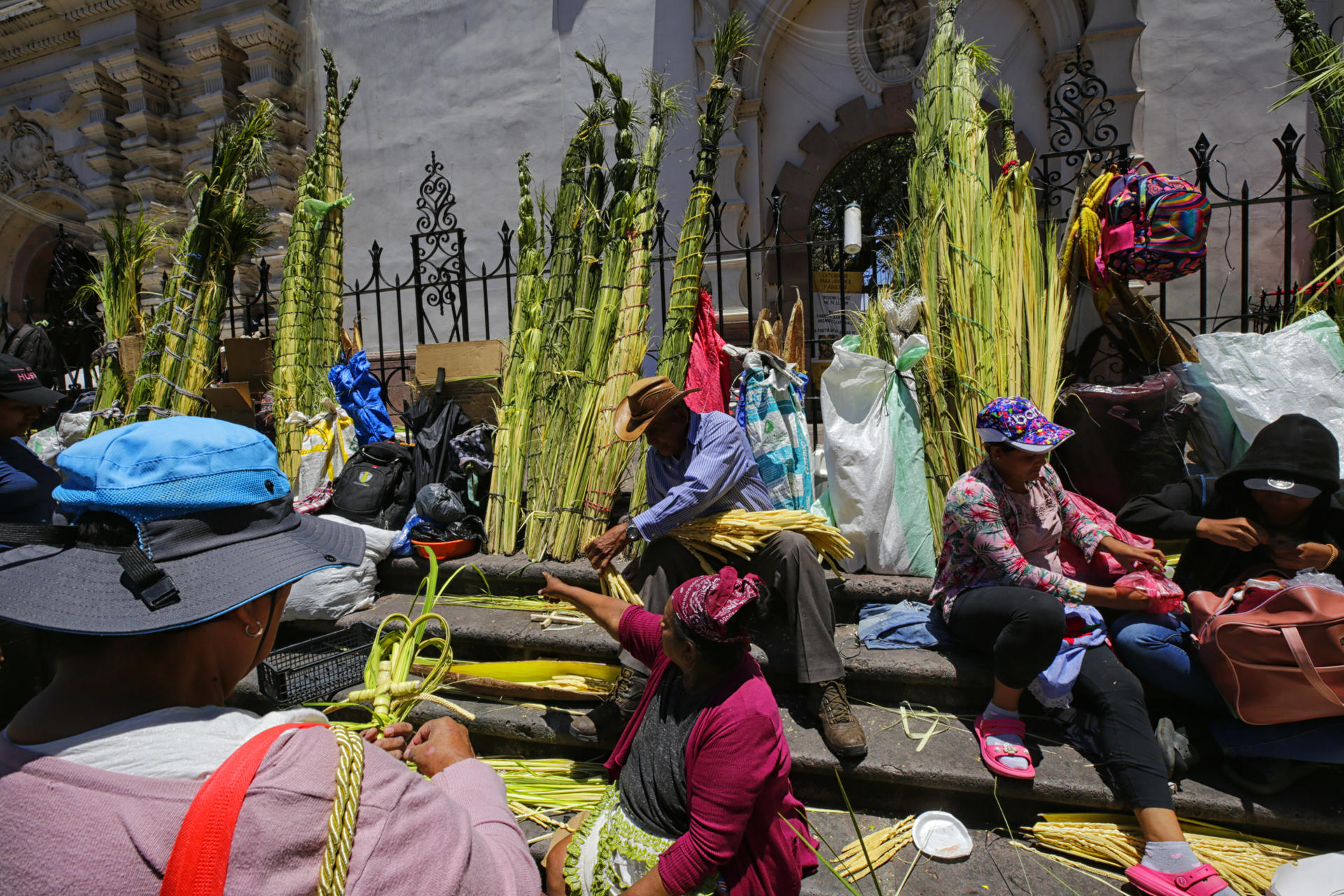 Personas venden ramos de palma en la entrada de la Catedral San Miguel Arcángel este viernes, en Tegucigalpa (Honduras). EFE/Gustavo Amador