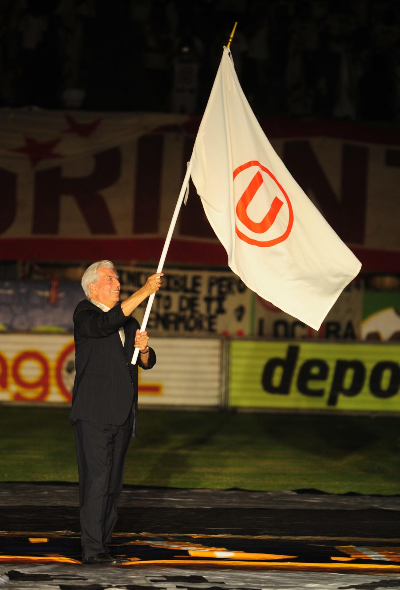El escritor Mario Vargas Llosa ondea la bandera del club de fútbol Universitario de Deportes el 2 de febrero de 2011, en el Estadio Monumental de Lima (Perú). EFE/Raúl García