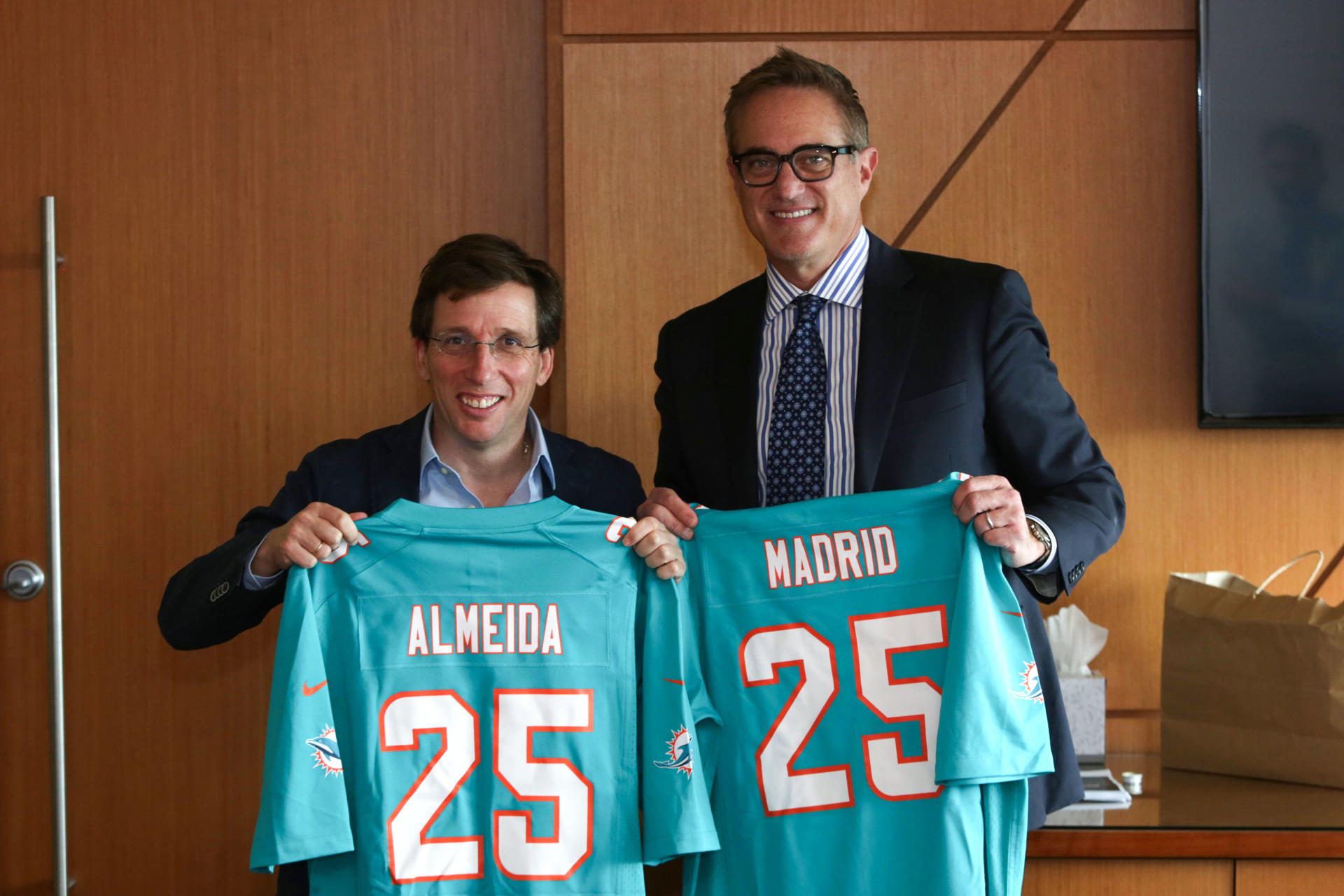 El alcalde de Madrid, José Luis Martínez-Almeida (i), posa junto al consejero delegado de los Miami Dolphins de la NFL y mánager del Grand Prix de Miami, Tom Garfinkell, con camisetas de los Dolphins durante una reunión en el Hard Rock Stadium Florida (Estados Unidos). EFE/Marlon Pacheco