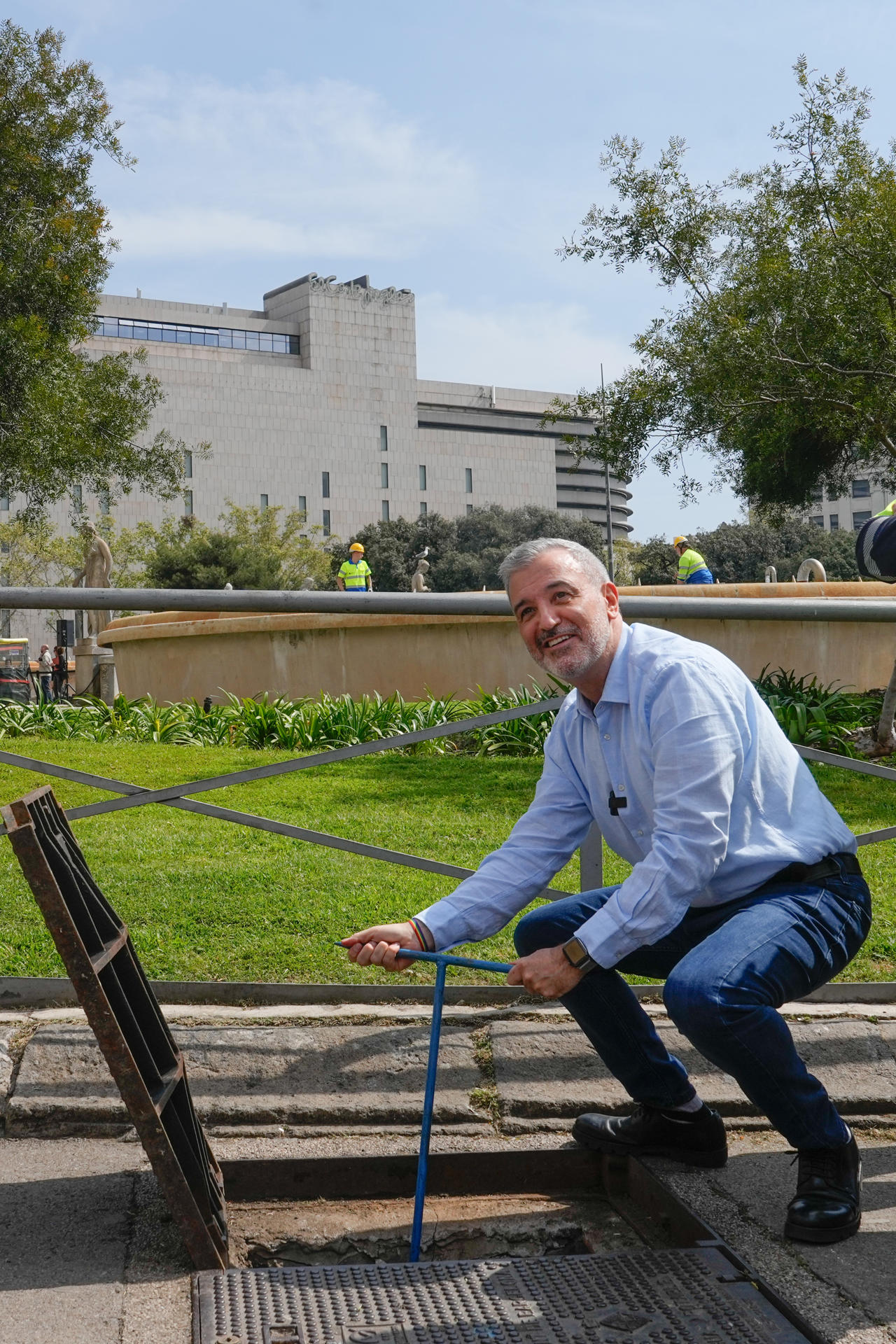 Barcelona ha iniciado un proceso progresivo, que durará varios meses, para recuperar sus fuentes ornamentales, apagadas durante la sequía, y en concreto en la Font Màgica de Montjuïc volverá a brotar agua el próximo septiembre, para las fiestas de La Mercè.En la imagen el alcalde de Barcelona, Jaume Collboni "abre" la llave de paso mientras unos operarios realizan tareas de reparación en las fuentes de Plaza Catalunya.EFE/ Enric Fontcuberta