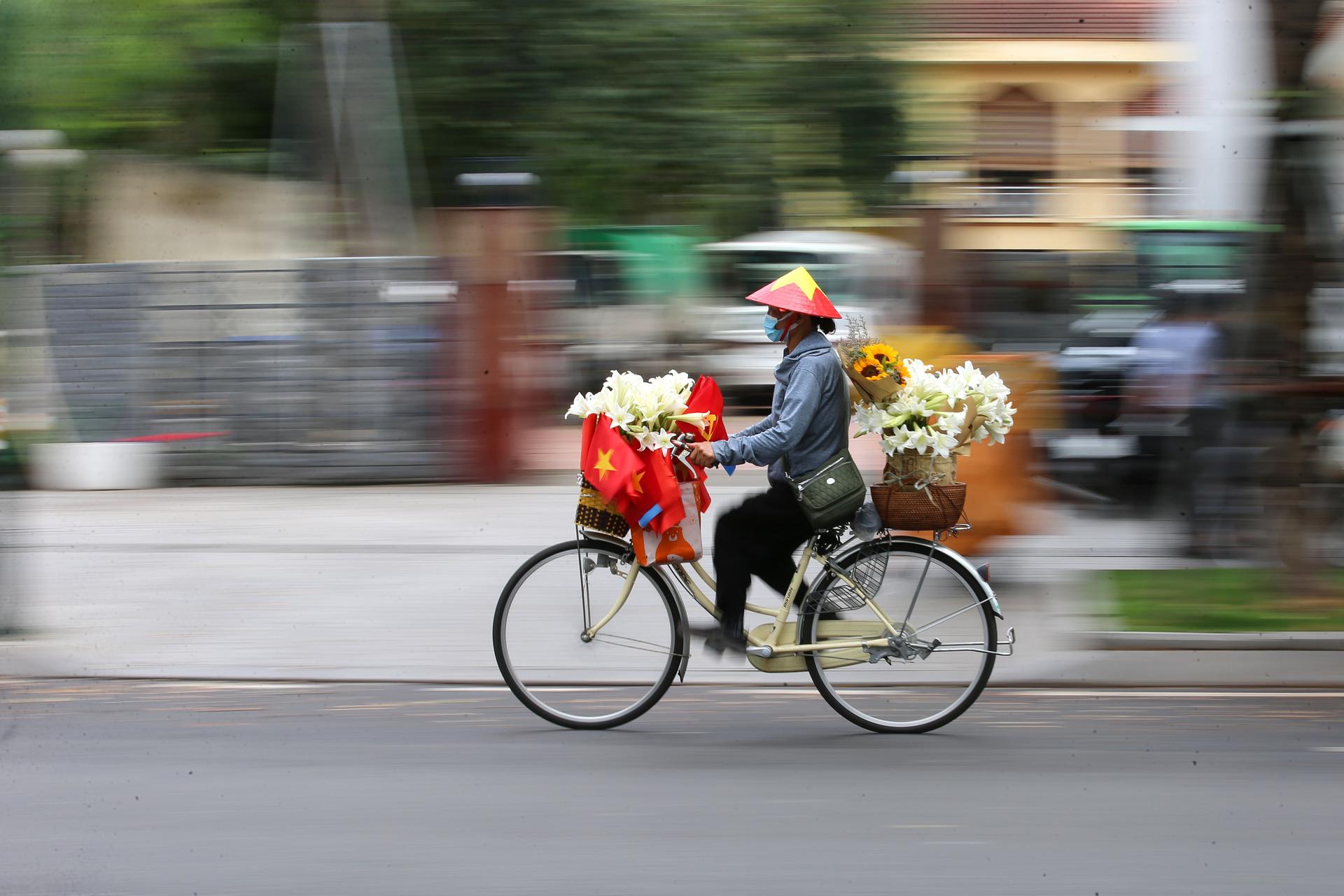 HANOI (Viet Nam), 25/04/2025.- A street vendor selling flowers cycles ahead of the 50th anniversary of the Liberation of the South and National Reunification Day, in Hanoi, Vietnam 25 April 2025. Vietnamese Reunification Day is observed annually on 30 April. EFE/EPA/LUONG THAI LINH
