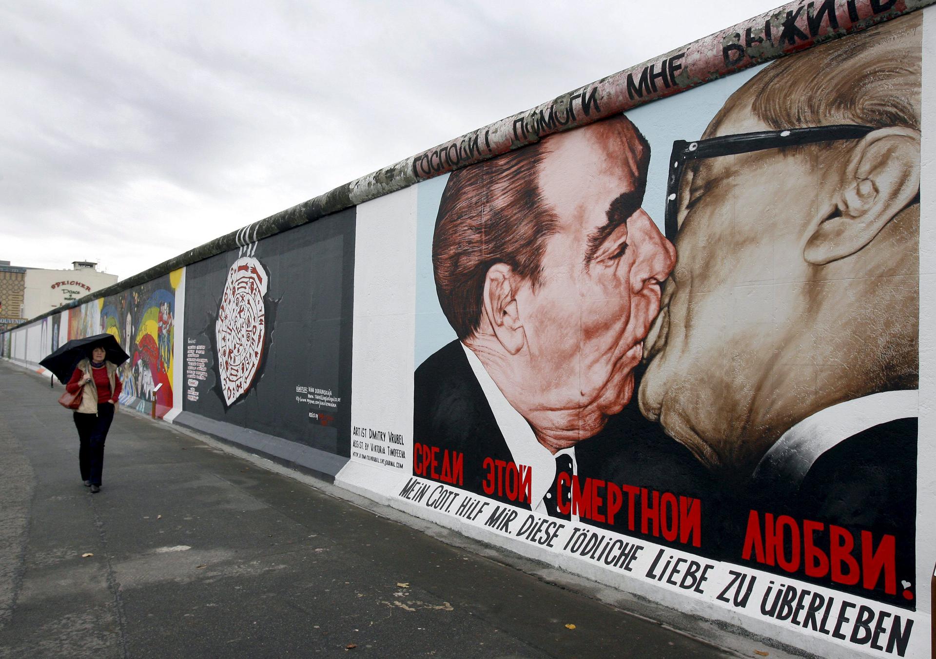 Berlín, 6/11/2009.- Una mujer pasa junto a la pintura "My God help me, this deadly love to survive" del artista ruso Dmitri Vrubel en la East Side Gallery de Berlín, Alemania. EFE/Wolfgang Kumm