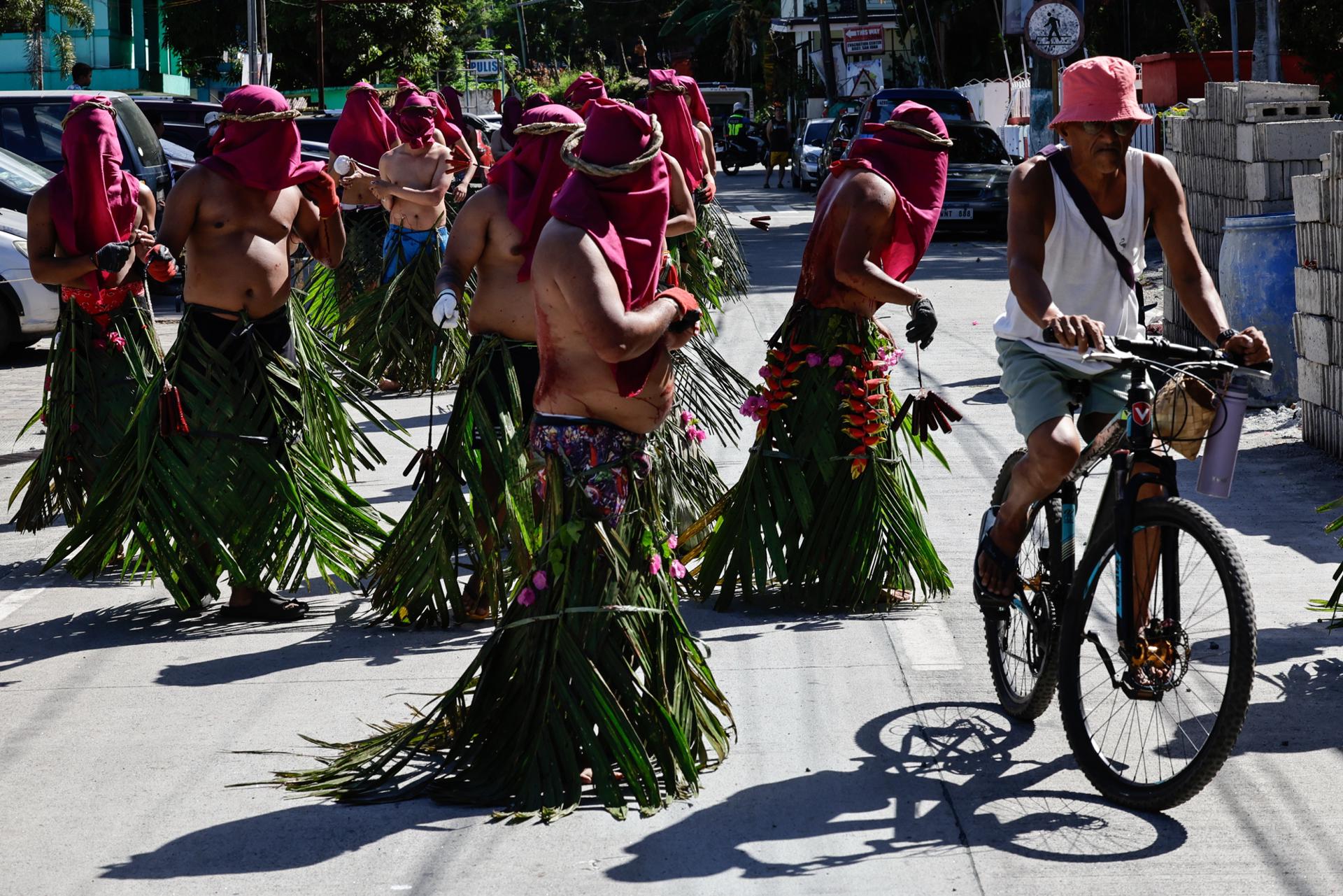 Un residente en bicicleta evita a los penitentes católicos que se flagelan mientras recorren las comunidades para conmemorar el Viernes Santo en la localidad de Kalayaan, provincia de Laguna, Filipinas, 18 de abril de 2025. EFE/EPA/ROLEX DELA PENA