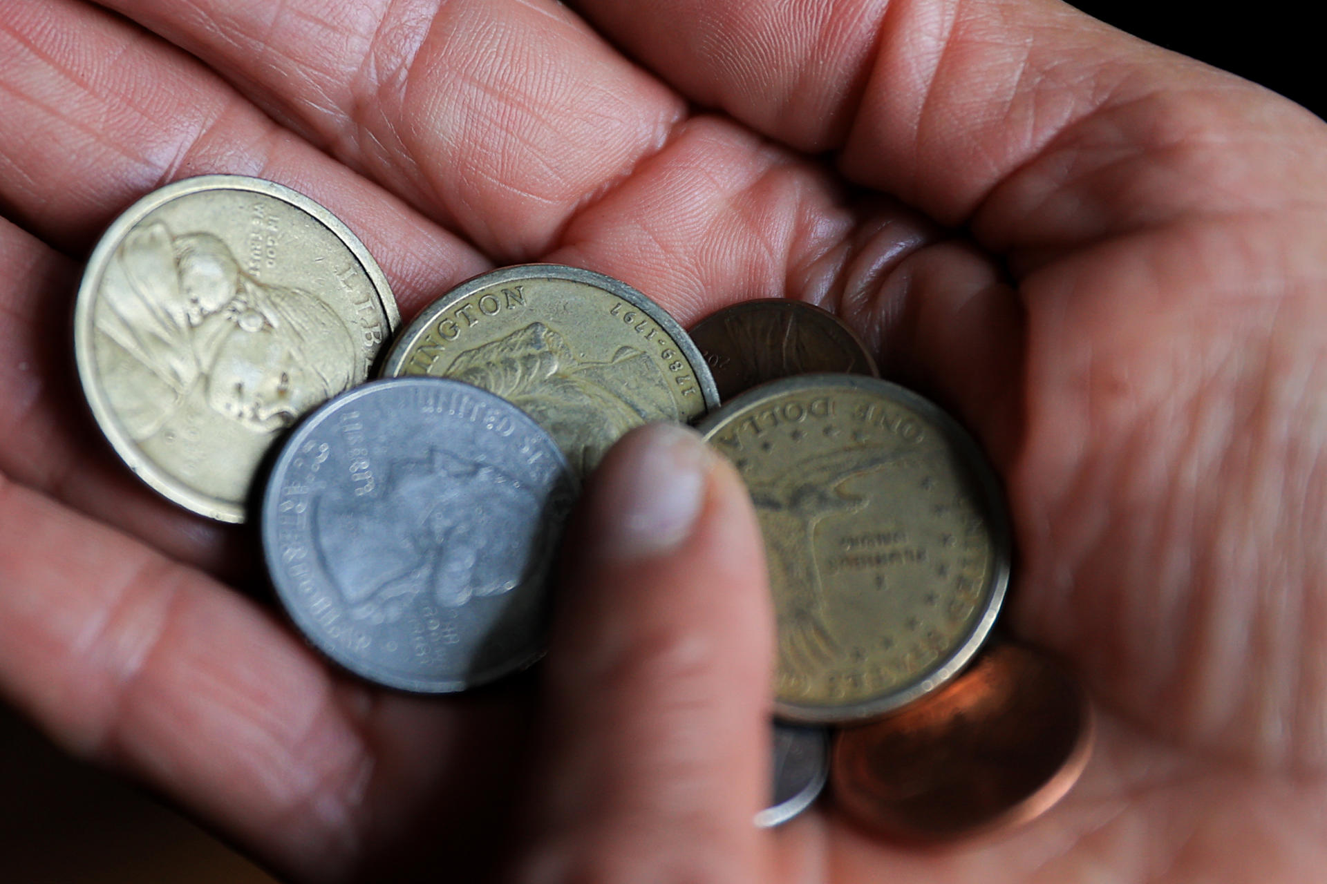 Una persona sostiene monedas de un dolar y centavos de dolar en Quito (Ecuador).EFE/ José Jácome