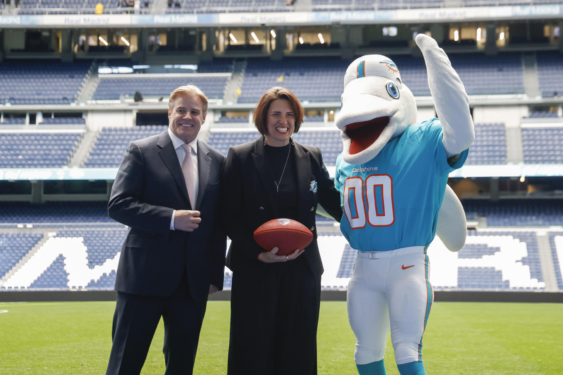 Brett Gosper, director de la NFL en Europa y Asia-Pacífico y Pri Shumate, vicepresidenta de los Miami Dolphins, en el césped del estadio Santiago Bernabéu con la mascota del equipo el pasado 17 de enero. EFE/ Blanca Millez