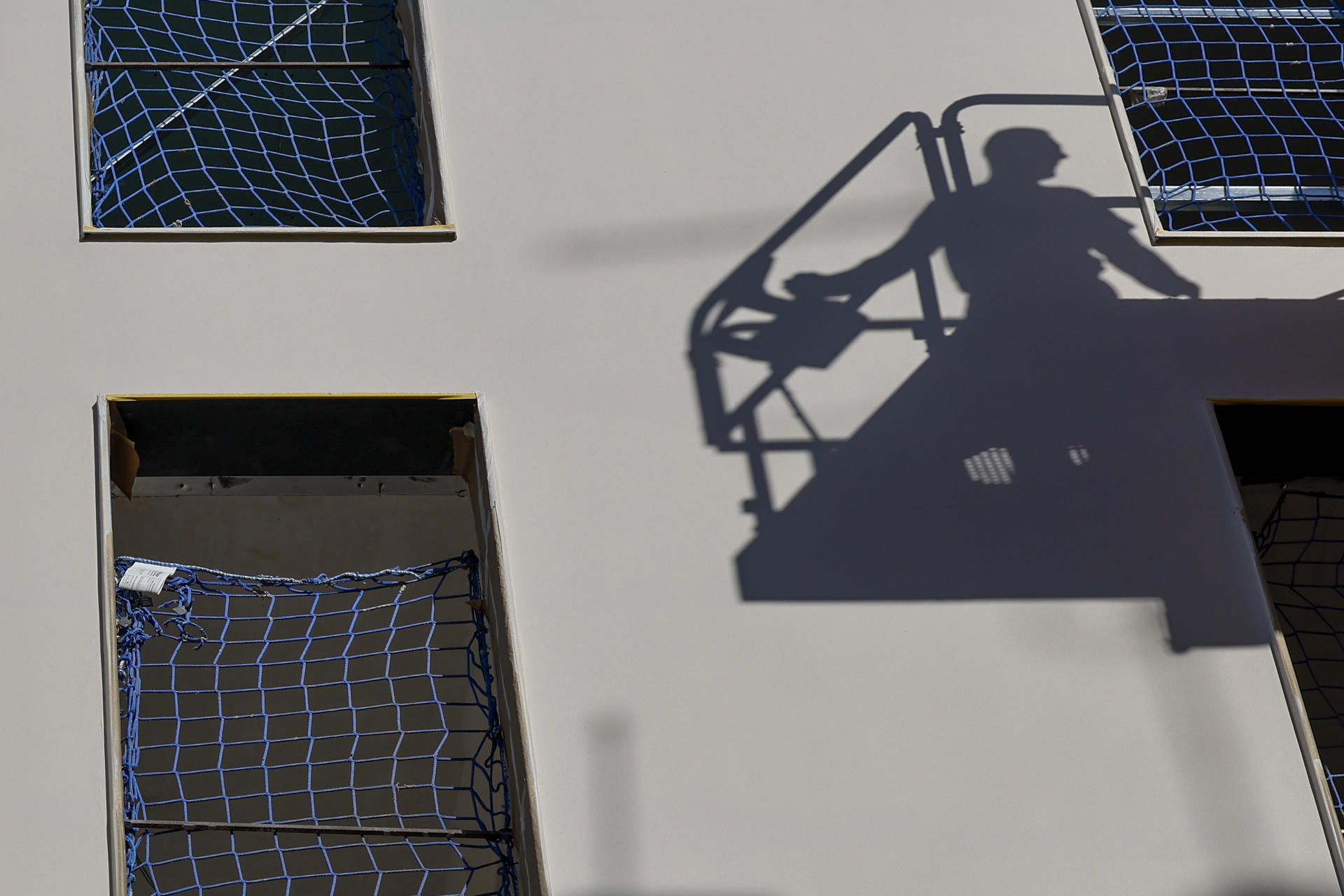 La sombra de un operario se proyecta sobre la fachada de una obra. EFE/Ana Escobar