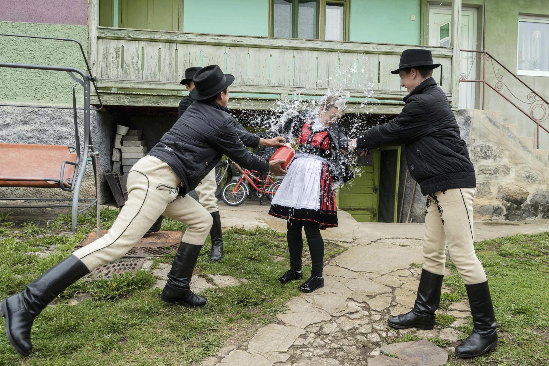 Foto archivo. Un grupo de hombres perteneciente a una etnia húngara vestidos con trajes tradicionales arrojan un cubo de agua sobre una mujer en Misentea. Según una vieja tradición húngara, cada lunes de Pascua los hombres vierten agua sobre las mujeres jóvenes, que después cambian sus recipientes de agua por huevos de colores. EFE/Nandor Veres PROHIBIDO SU USO EN HUNGRÍA[PROHIBIDO SU USO EN HUNGRÍA]
