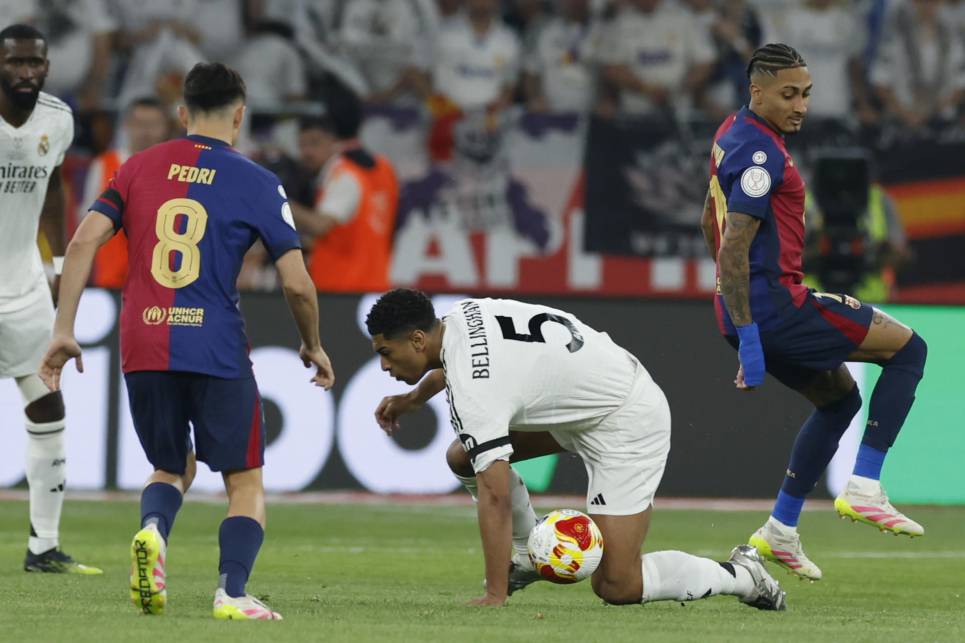 La centrocampista británico del Real Madrid Jude Bellingham (d) cae al suelo junto a Pedri, del FC Barcelona, durante la final de la Copa del Rey que disputaron Real Madrid y FC Barcelona hoy sábado en el estadio de La Cartuja, en Sevilla. EFE/Julio Muñoz