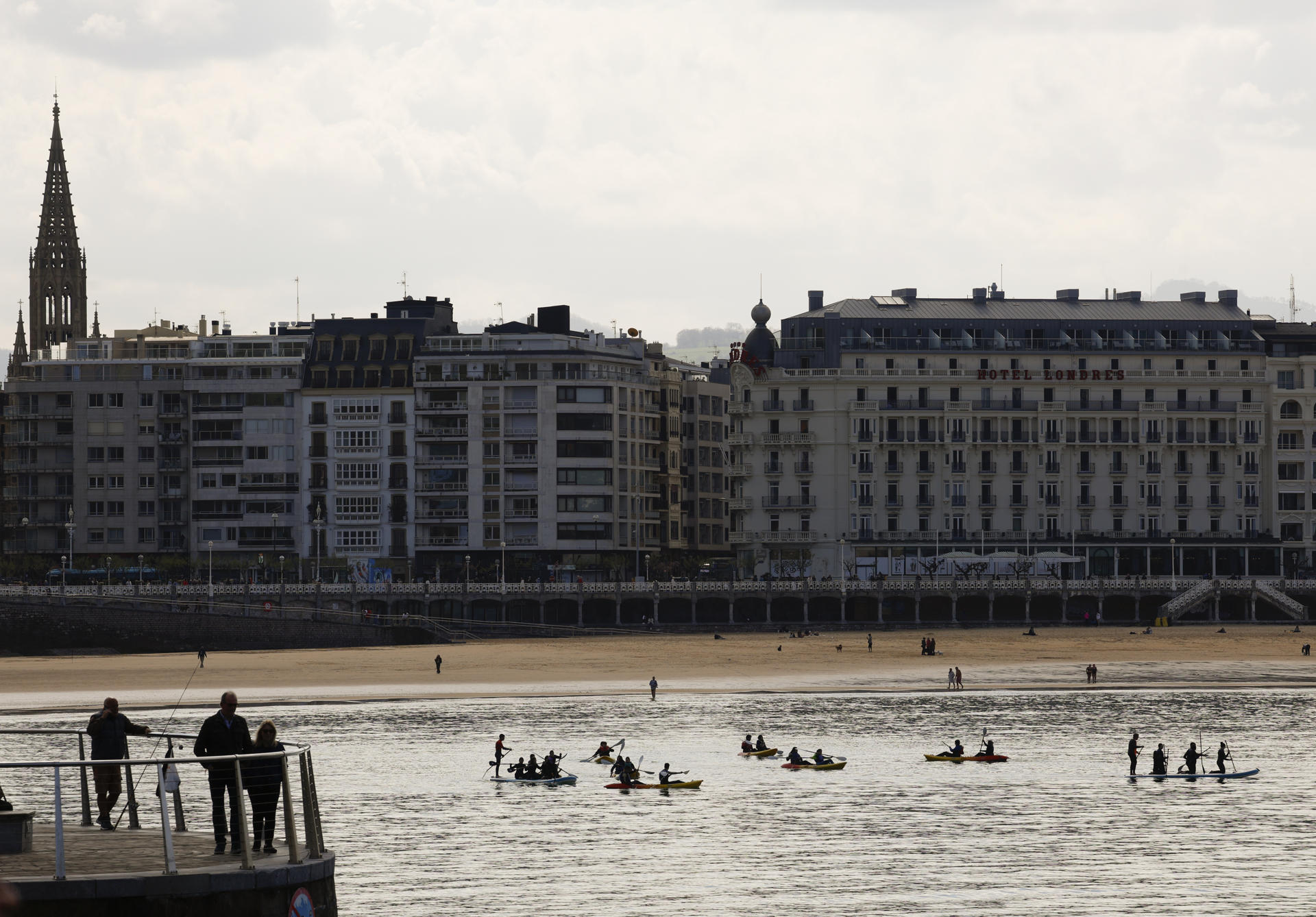 Un grupo de bañistas practican con piraguas y tablas de paddle surf este miércoles en la playa de la Concha de San Sebastián.EFE/Juan Herrero.