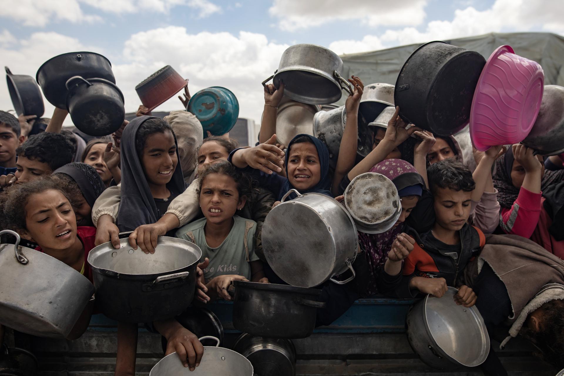 Palestinos desplazados internos sostienen cuencos y ollas mientras esperan en fila para recibir una porción de comida de una cocina benéfica, en Khan Younis, sur de la Franja de Gaza, 11 de abril de 2025. Más de 50,800 palestinos han sido asesinados en la Franja de Gaza, según el Ministerio de Salud palestino, desde que Israel lanzó una campaña militar en la franja en respuesta a un ataque transfronterizo llevado a cabo por el grupo militante palestino Hamas el 07 de octubre de 2023, en el cual aproximadamente 1,200 israelíes fueron asesinados y más de 250 tomados como rehenes. EFE/EPA/HAITHAM IMAD