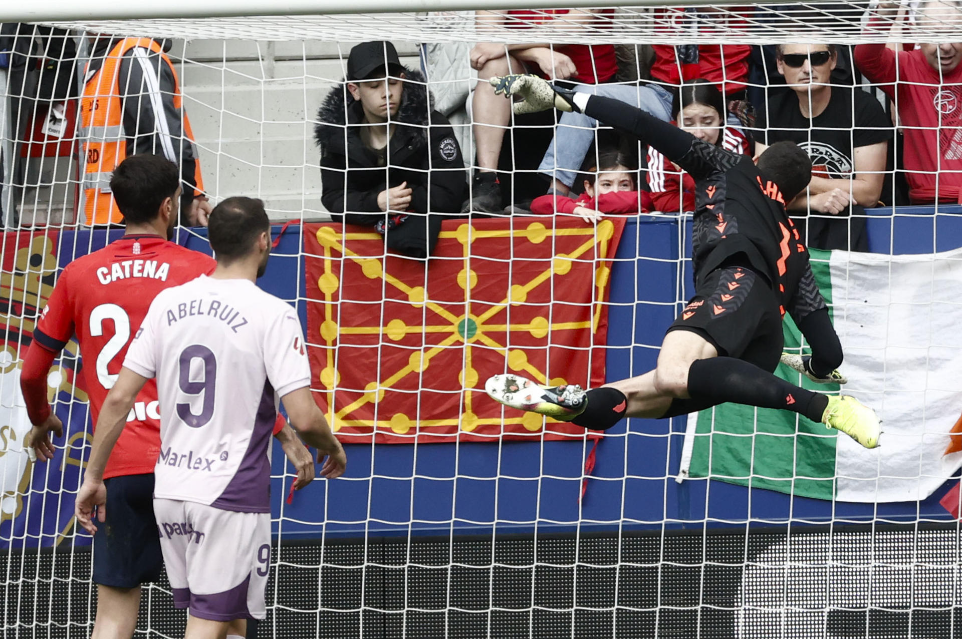 El Portero del Osasuna Sergio Herrera (c) detiene un lanzamiento de falta ante su compañero Alejandro Catena y el jugador del Girona Abel Ruiz(d), durante el partido que disputaron en el estadio de El Sadar, correspondiente a la jornada 31 de Laliga. EFE/ Jesús Diges