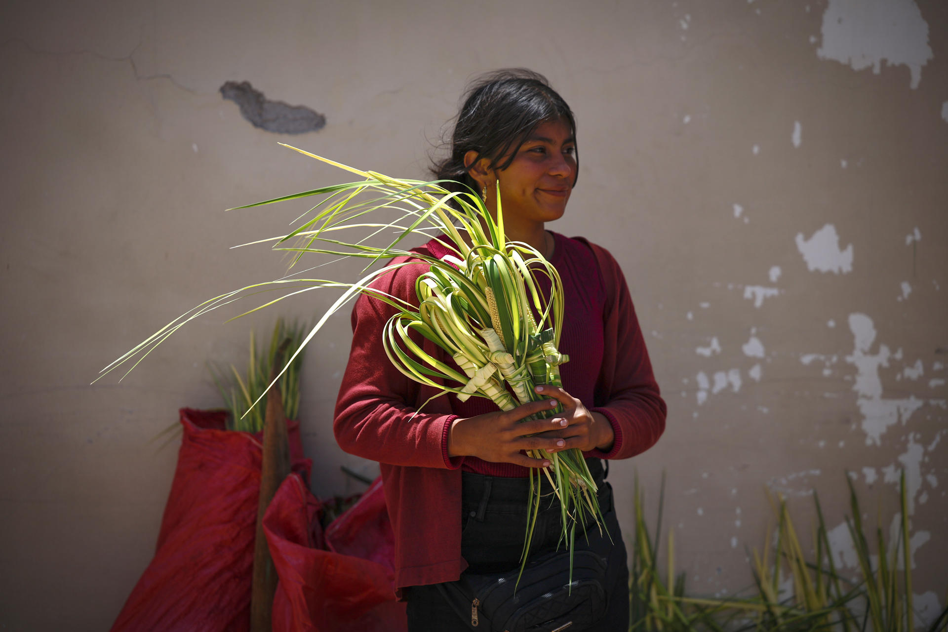 Una campesina vende ramos de palma en la víspera del Domingo de Ramos, que marca el inicio de la Semana Santa este viernes, en la entrada de la Catedral de la Inmaculada Concepción en Comayagüa (Honduras). EFE/ Bienvenido Velasco