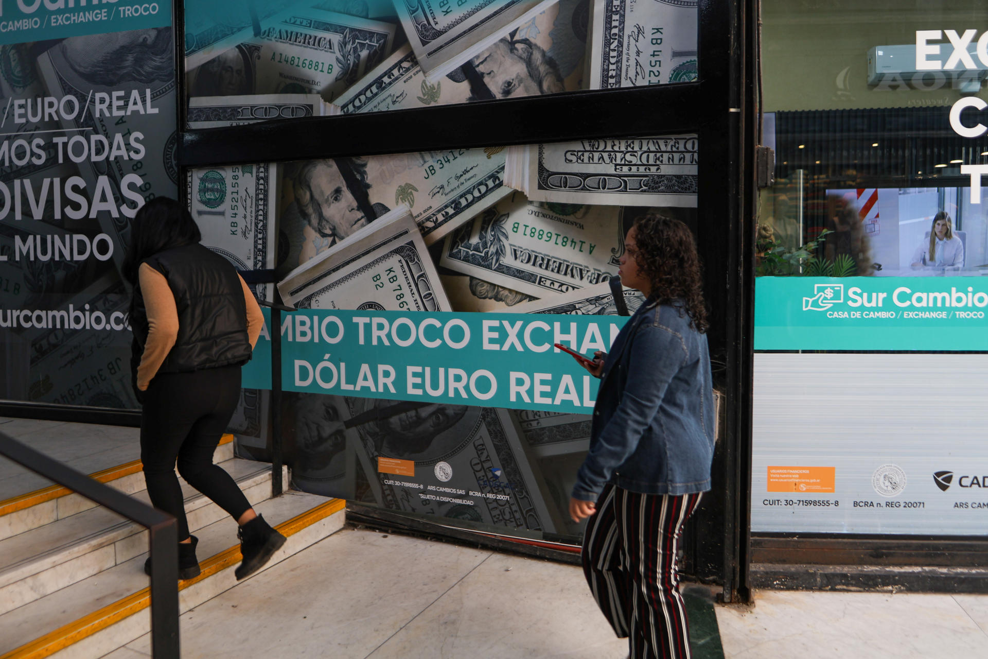 Dos personas caminan frente a una casa de cambio este 14 de abril de 2025, en Buenos Aires (Argentina). EFE/ Juan Ignacio Roncoroni