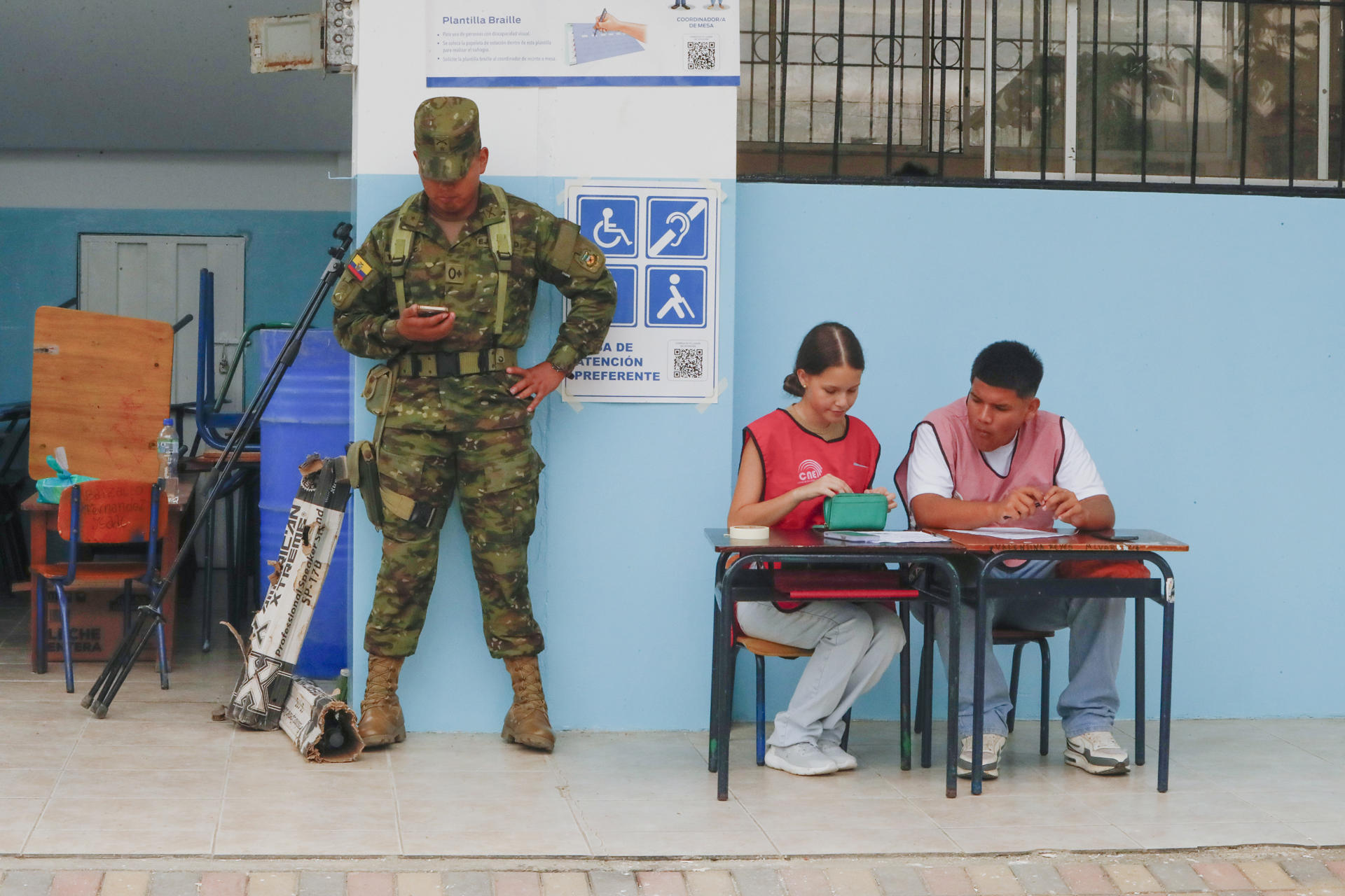 Un integrante del Ejército ecuatoriano vigila junto a colaboradores de atención prioritaria en un centro de votación este domingo, en Olón (Ecuador). EFE/ Carlos Durán Araújo
