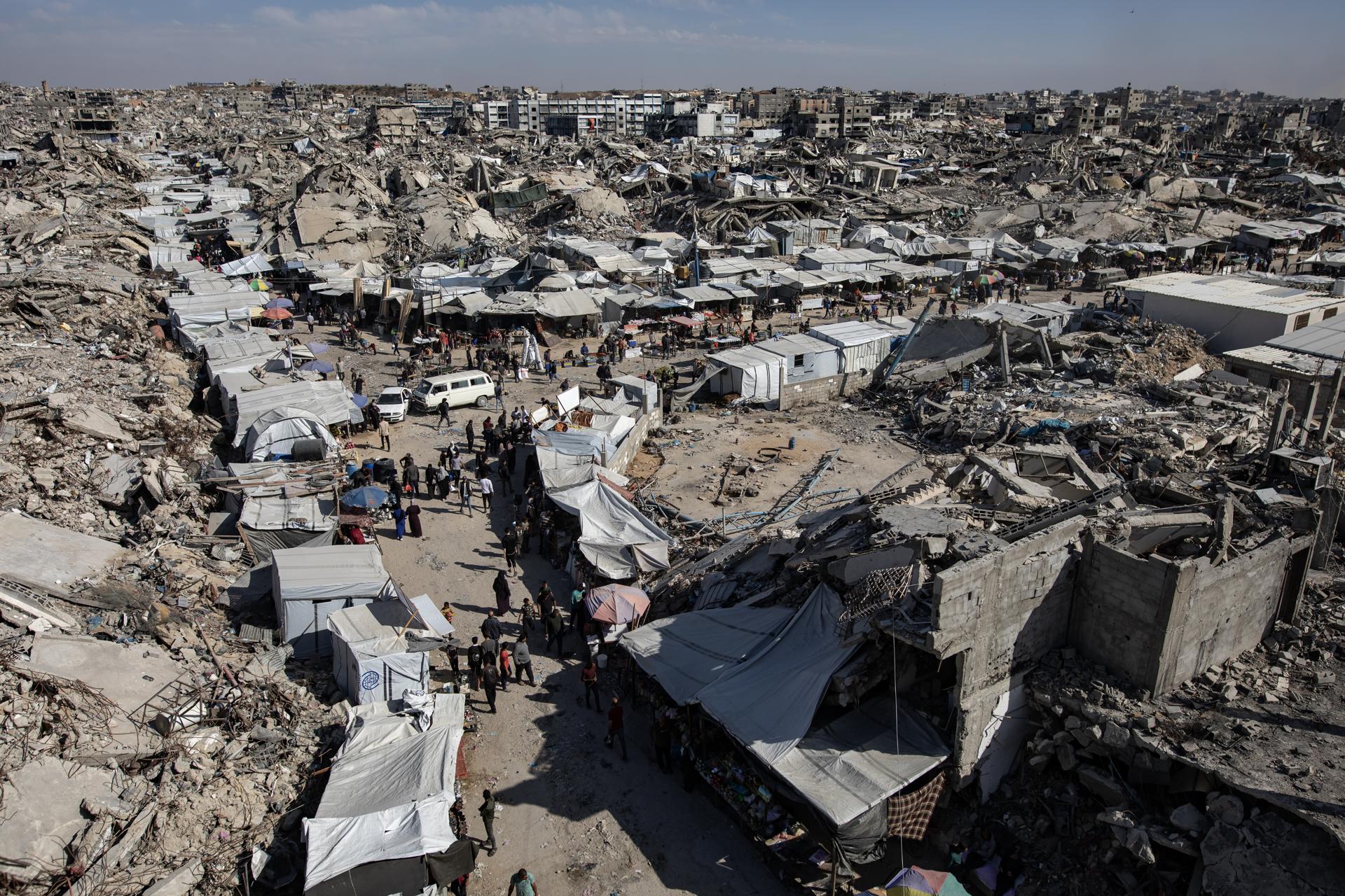 Los palestinos desplazados se reúnen en un mercado cerca de los escombros de edificios destruidos en Jabalia, al norte de la Franja de Gaza, 27 de abril de 2025. El Programa Mundial de Alimentos de la ONU (PMA) anunció el 25 de abril que ha agotado todos los suministros de alimentos para las familias en Gaza debido a semanas de cierres en los cruces fronterizos. Más de un millón de gazatíes enfrentan 'niveles altos' de inseguridad alimentaria aguda, con desnutrición aguda varias veces superior a los niveles anteriores a la guerra, advirtió la agencia de refugiados palestinos de la ONU, UNRWA. EFE/EPA/HAITHAM IMAD