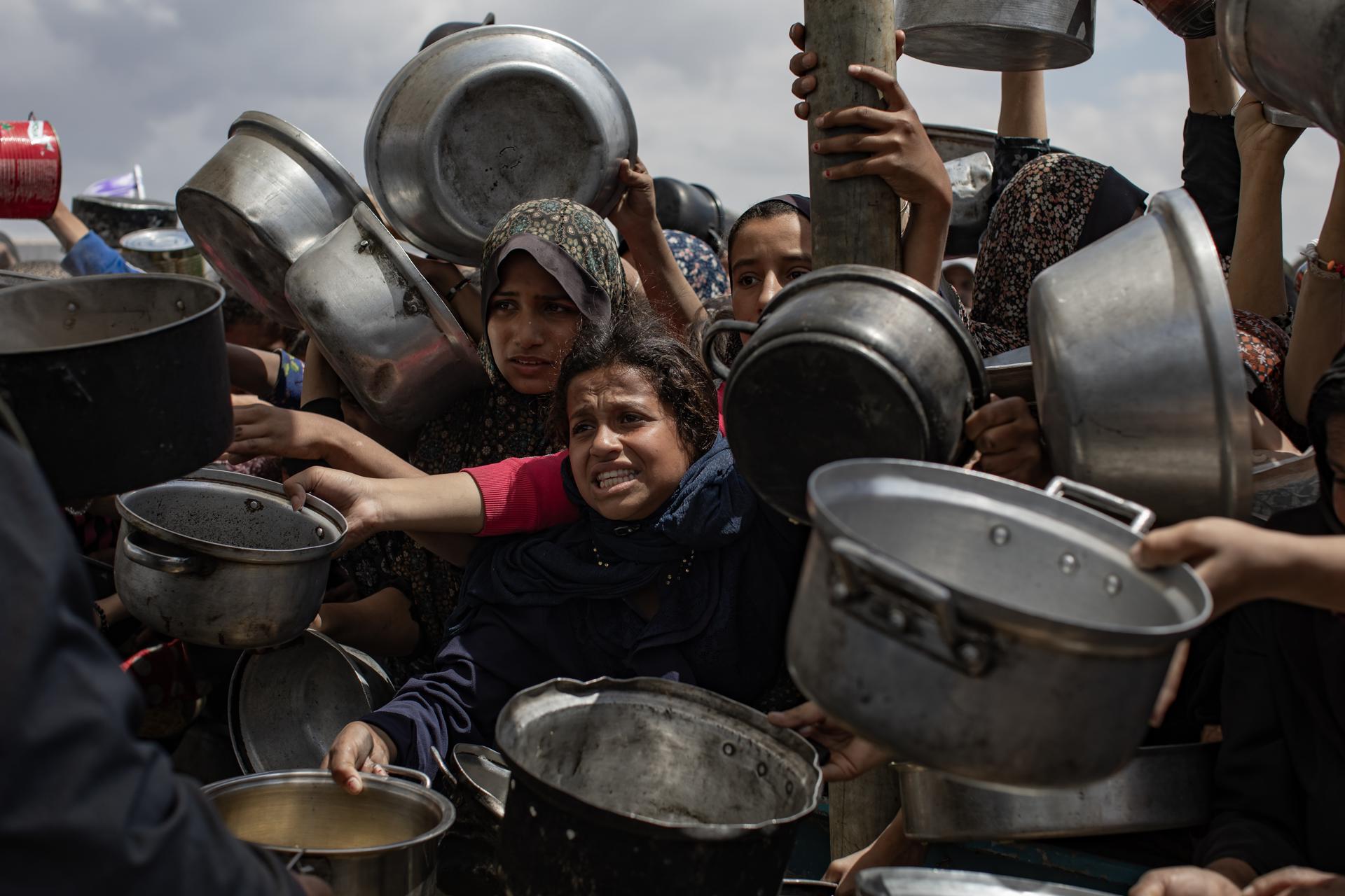 Palestinos desplazados internamente se agrupan en una fila para recibir una ración de comida de una cocina benéfica, en Khan Younis, sur de la Franja de Gaza, 11 de abril de 2025. EFE/EPA/HAITHAM IMAD