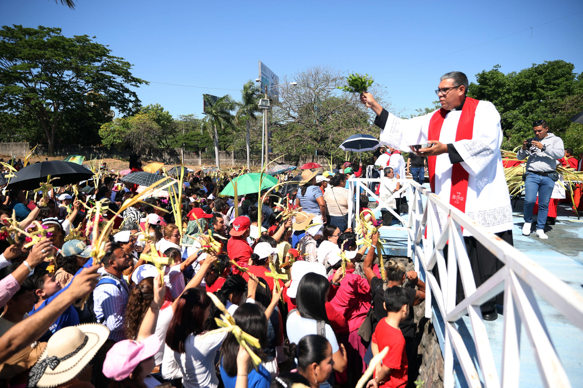 Personas levantan sus ramos para recibir la bendición de las palmas durante la misa del Domingo de Ramos, en el inicio de las festividades religiosas de Semana Santa este domingo en Managua (Nicaragua). EFE/STR