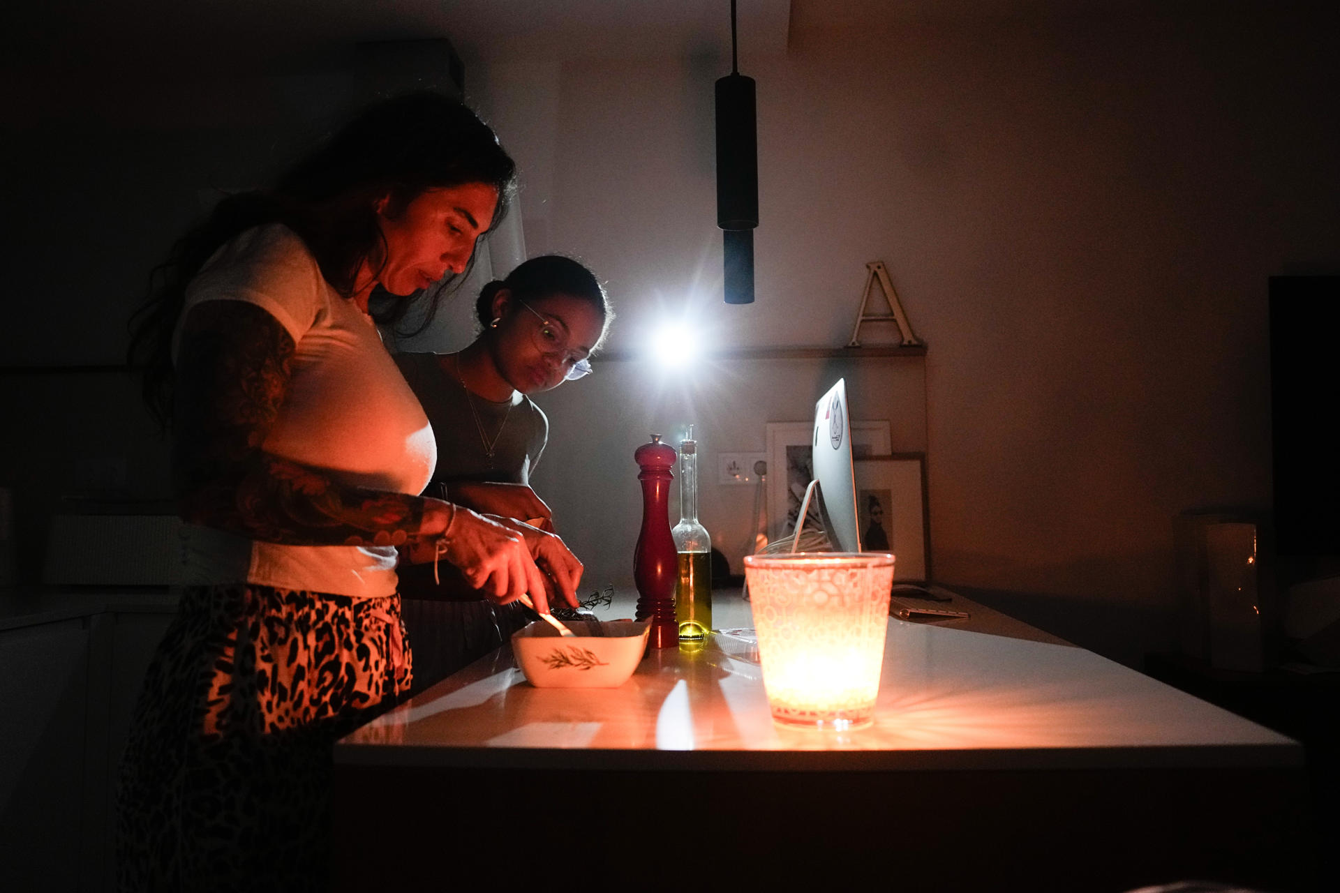 Una familia prepara la cena con ayuda de una vela la pasada noche en la localidad de El Masnou (Barcelona) durante el corte de suministro eléctrico que afectó a España. EFE/Enric Fontcuberta