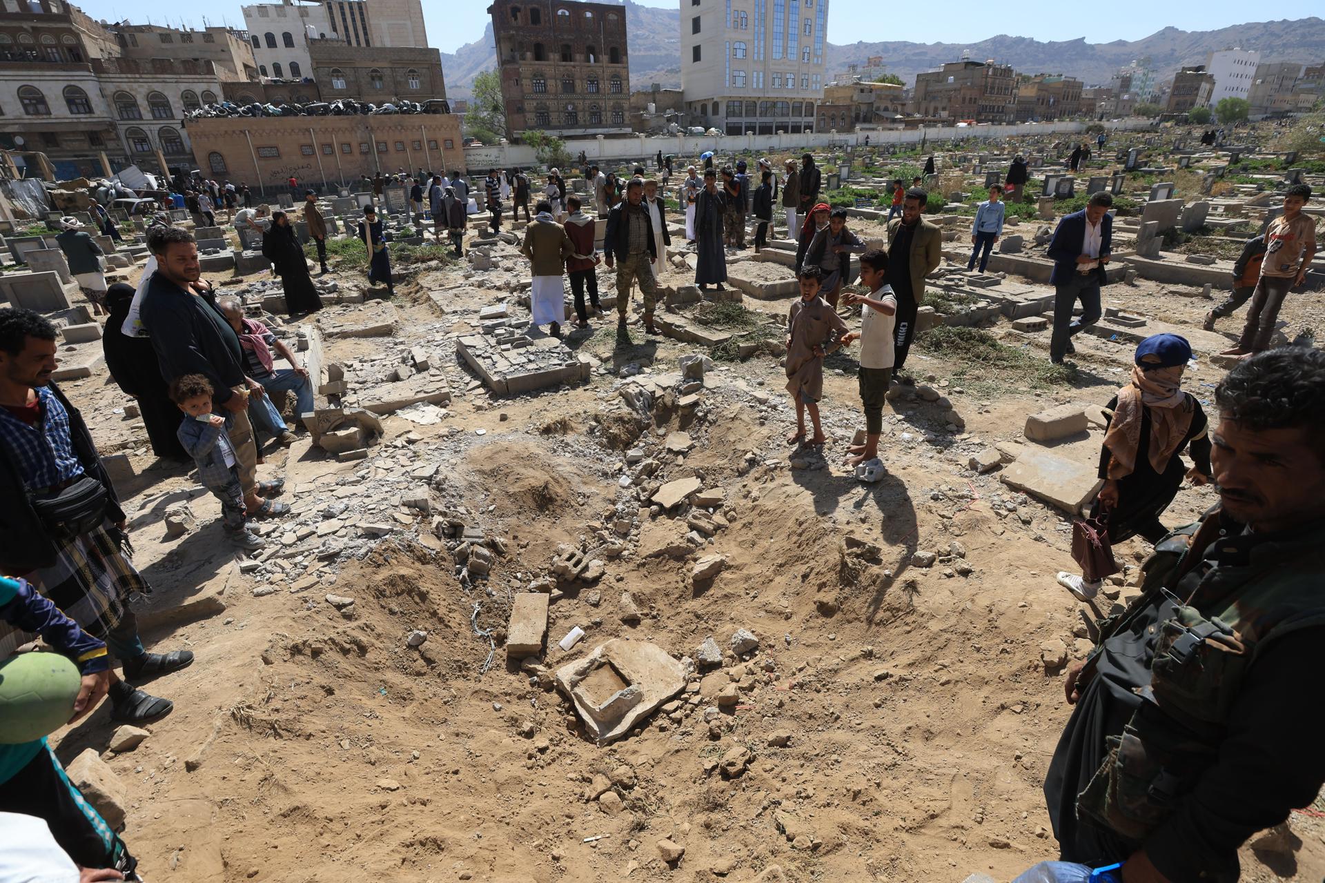 Personas al inspeccionar este domingo, 20 de abril, una zona de ataques aéreos de EE.UU. sobre un cementerio en Saná (Yemen). EFE/Yahya Arhab