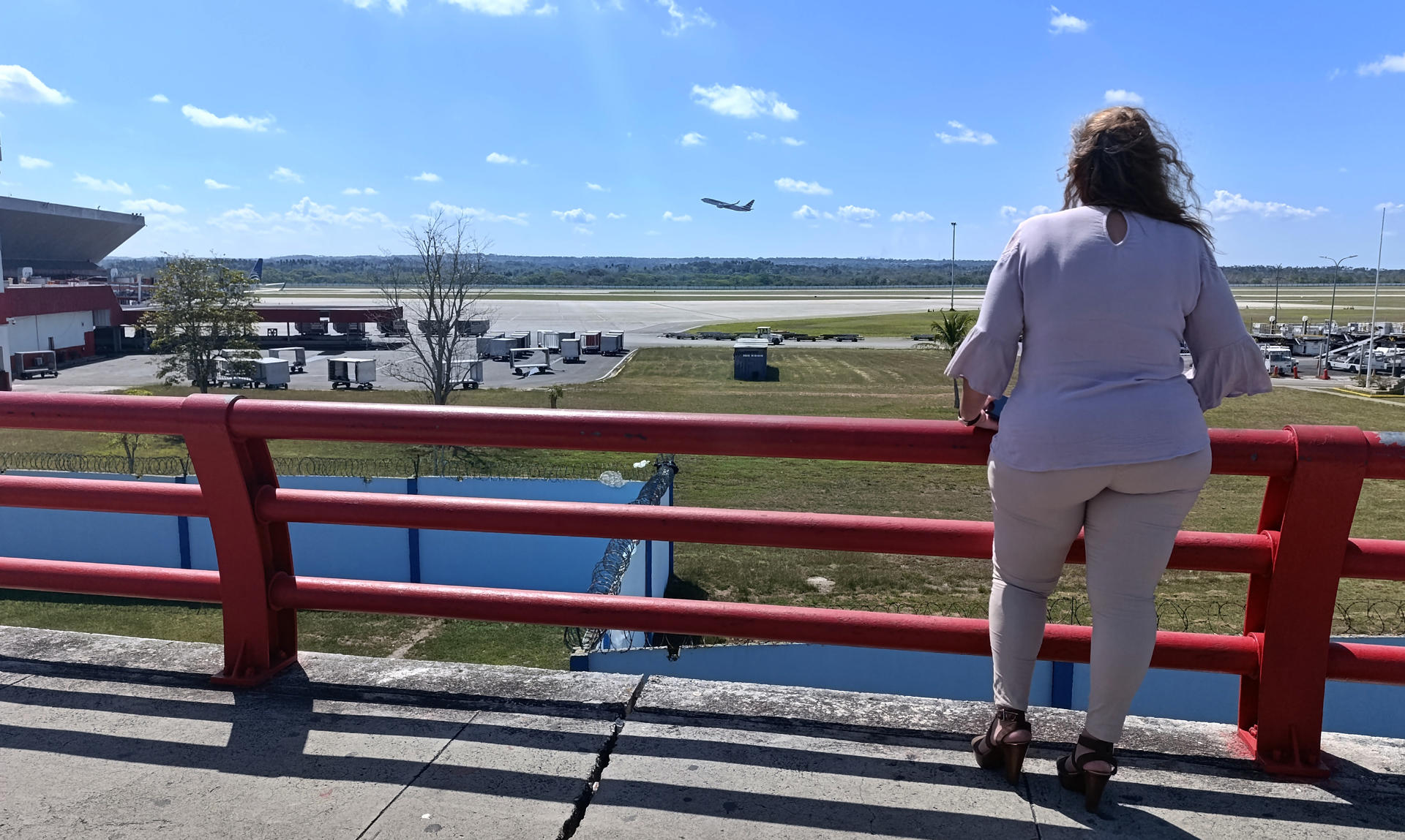 Fotografía del 28 de marzo de 2025 de una mujer observando el despegue de un avión en el aeropuerto internacional José Martí de La Habana (Cuba). EFE/ Ernesto Mastrascusa