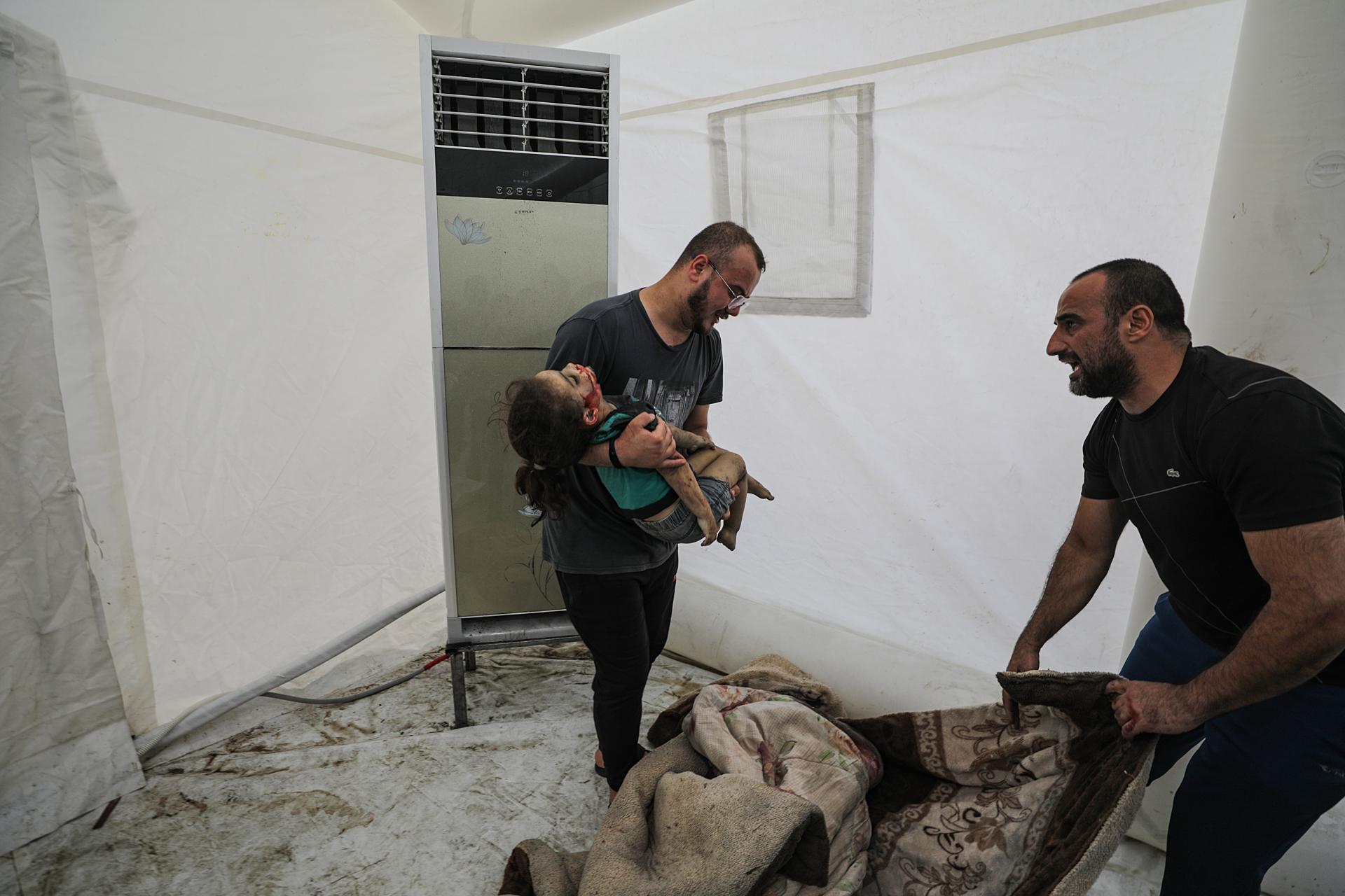 Imagen de archivo de un hombre llevando en brazos a un niño alcanzado por los bombardeos israelíes en la franja de Gaza. EFE/EPA/MOHAMMED SABER