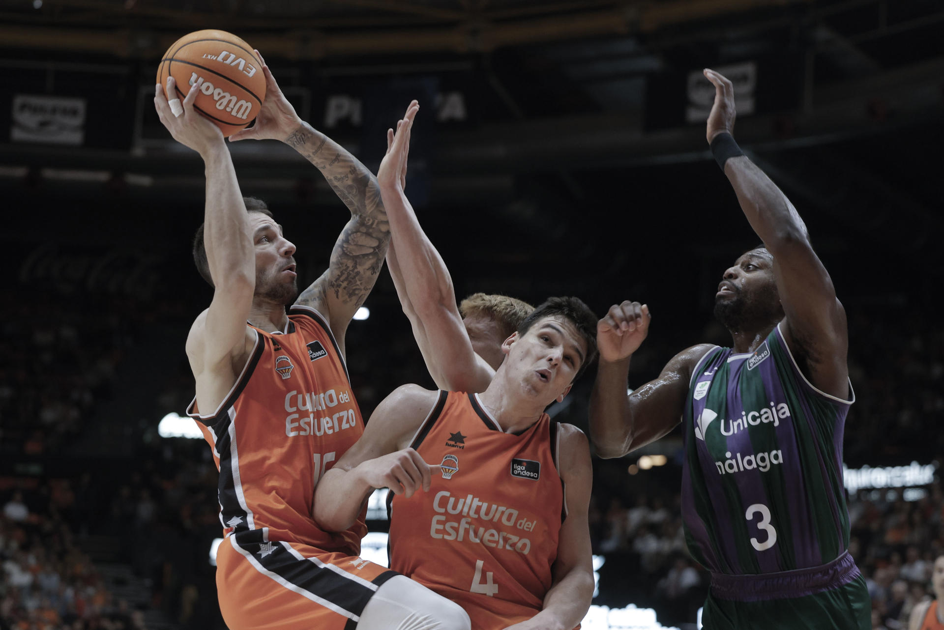 El base del Valencia Stefan Jovic (i) se dispone a lanzar ante Alberto Díaz (2-i) y Melvin Ejim (d), ambos de Unicaja, durante el partido de la Liga Endesa de baloncesto que Valencia Basket y Unicaja disputaron en el Pabellón Municipal Fuente de San Luis. EFE/Kai Forsterling
